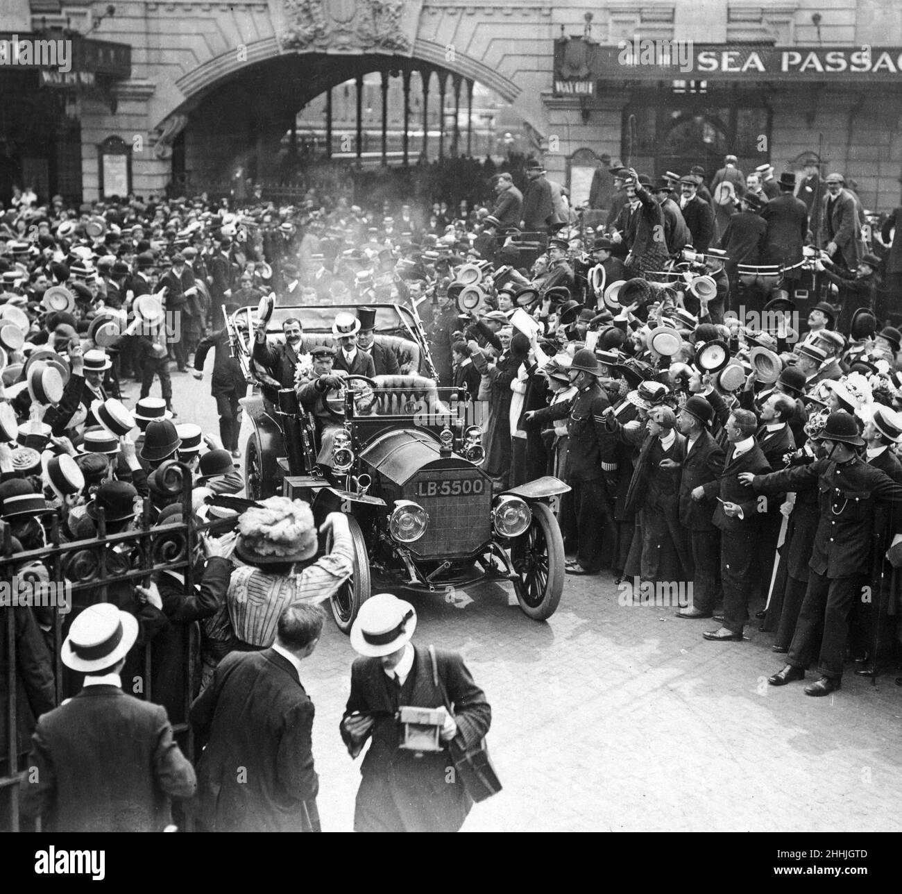 London heißt Louis Bleriot willkommen: Jubelnde Menschenmassen begrüßen den unerschrockenen Flieger, der die Victoria Station mit dem Auto zu einem besonderen Festessen im Savoy Hotel verlässt. Montag, 26th. Juli 1909 Stockfoto