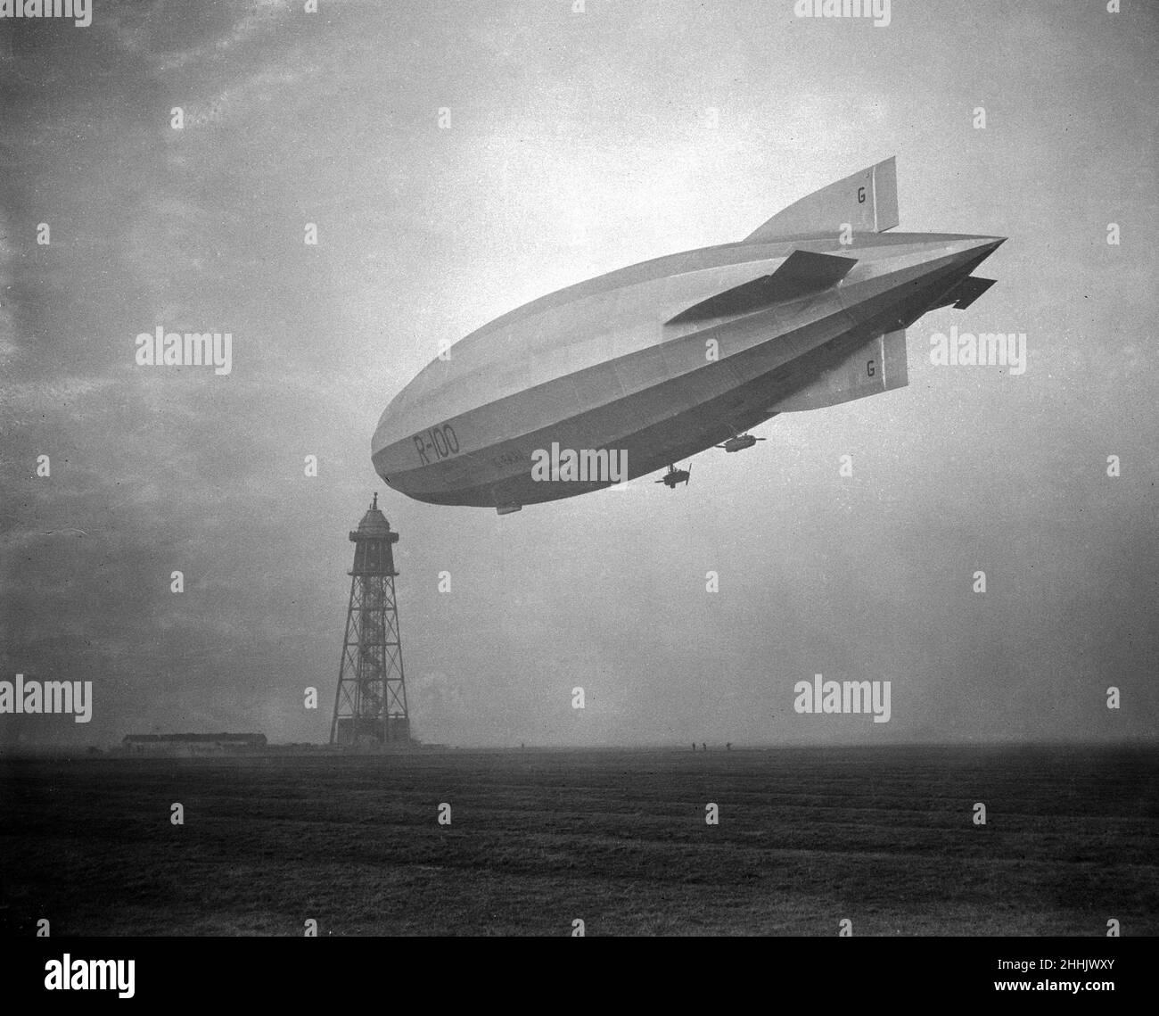 R100 auf ihrem Jungfernflug am Morgen des 16. Dezember 1929. Nach der Abfahrt von Howden flog sie langsam nach York, stellte dann die Weichen für die Royal Airship Works in Cardington, Bedfordshire, die mit etwa 50 km/h (80 mph) auf vier Motoren kreuzte und Cardington in zwei Stunden Flugzeit erreichte. In den riesigen Hangars in Cardington (von denen einige überleben) konkurrierten zwei Teams, das andere vom Luftministerium angeführt, um das bessere Design zu ermitteln, was zum Teil über lange Demonstrationsflüge möglich war. Stockfoto