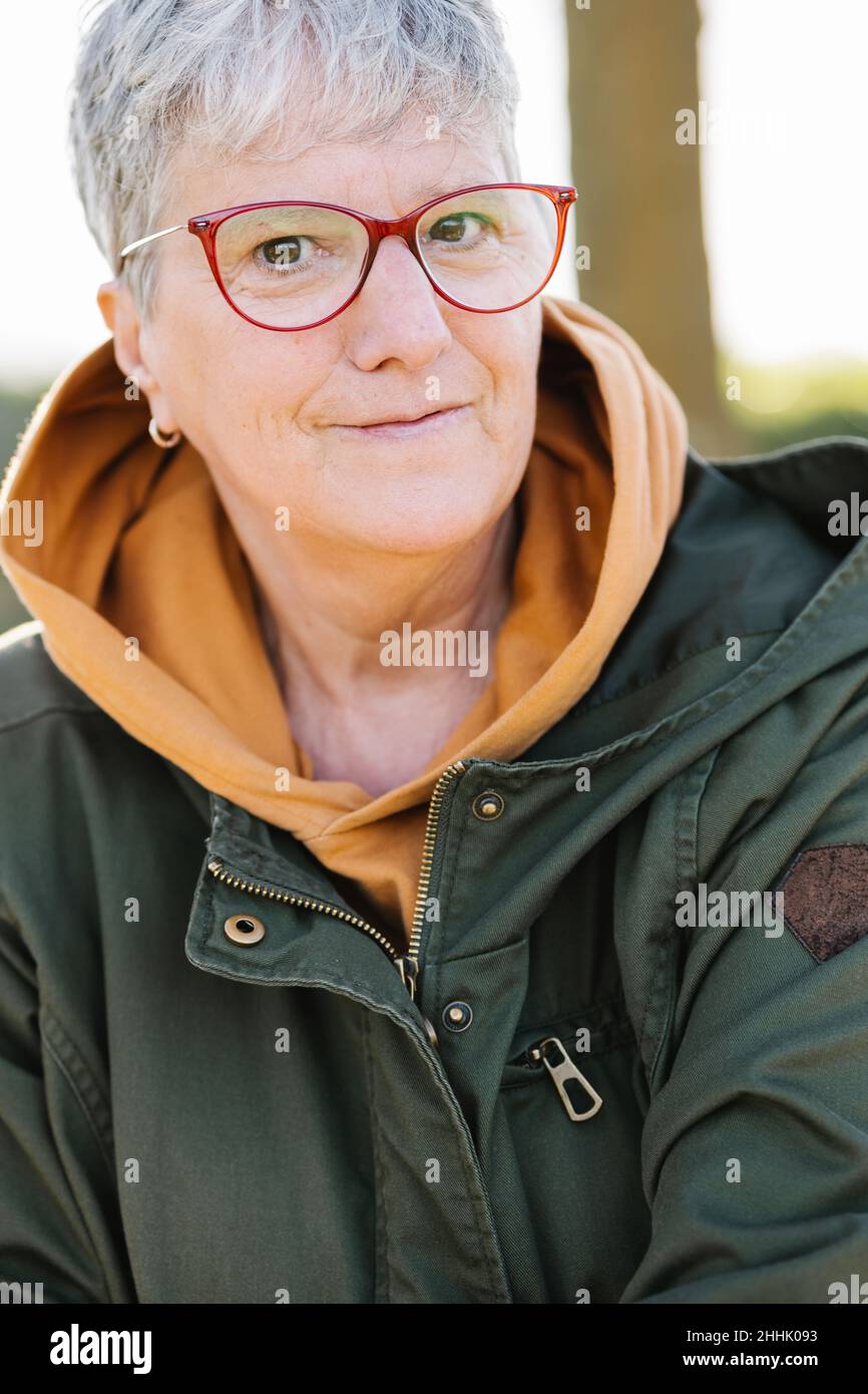 Crop grauhaarige ältere Frau in Brillen tragen warme Oberbekleidung sanft lächeln an der Kamera Stockfoto