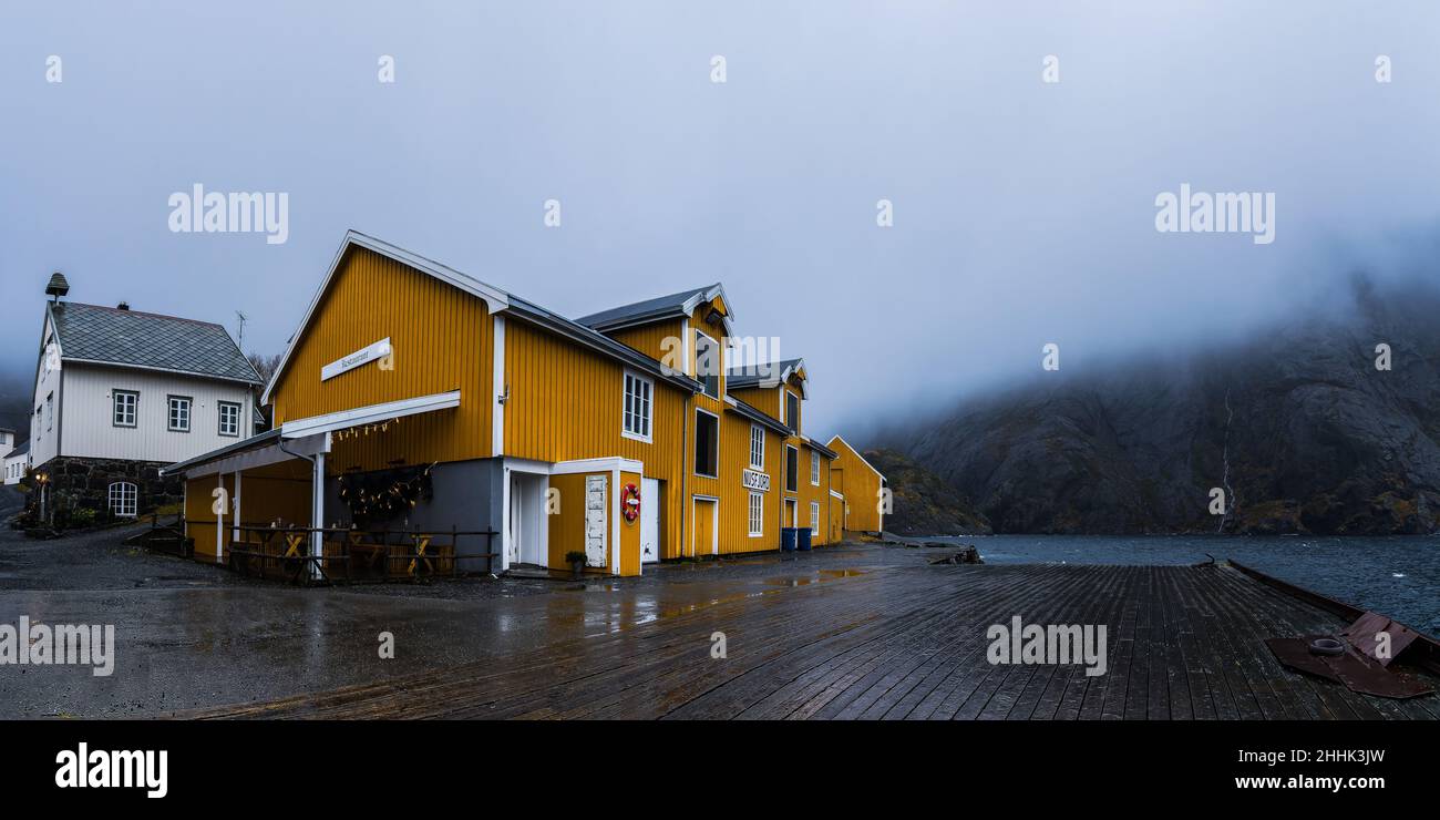 Außenansicht der typischen bunten Häuser des Dorfes Nusfjord auf einem hölzernen Damm gegen den nebligen Himmel in Norwegen Stockfoto