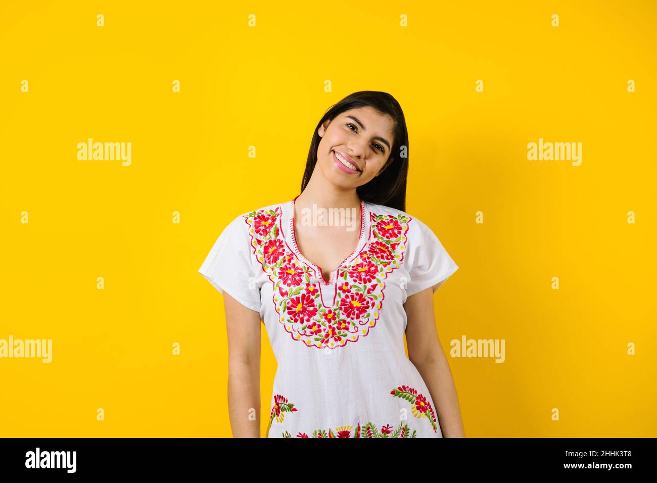Porträt einer jungen lateinerin mit mexikanischem Kleid und Kopierraum auf gelbem Hintergrund in Lateinamerika Stockfoto