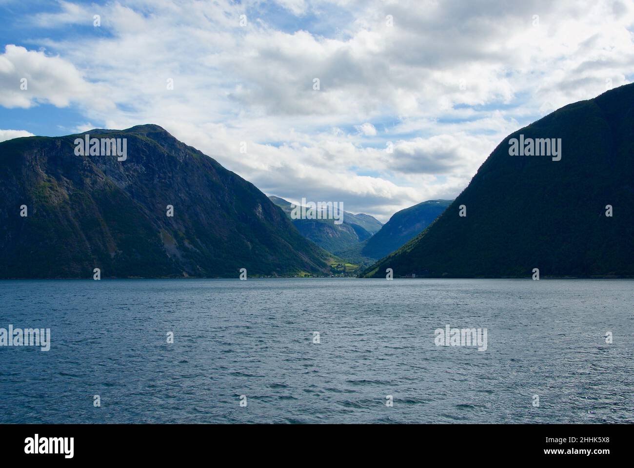 Berge und Himmel mit Wolken hinter dem kleinen Dorf Eidsdal am Geirangerfjord in Møre Og Romsdal fylke in Norwegen. Stockfoto