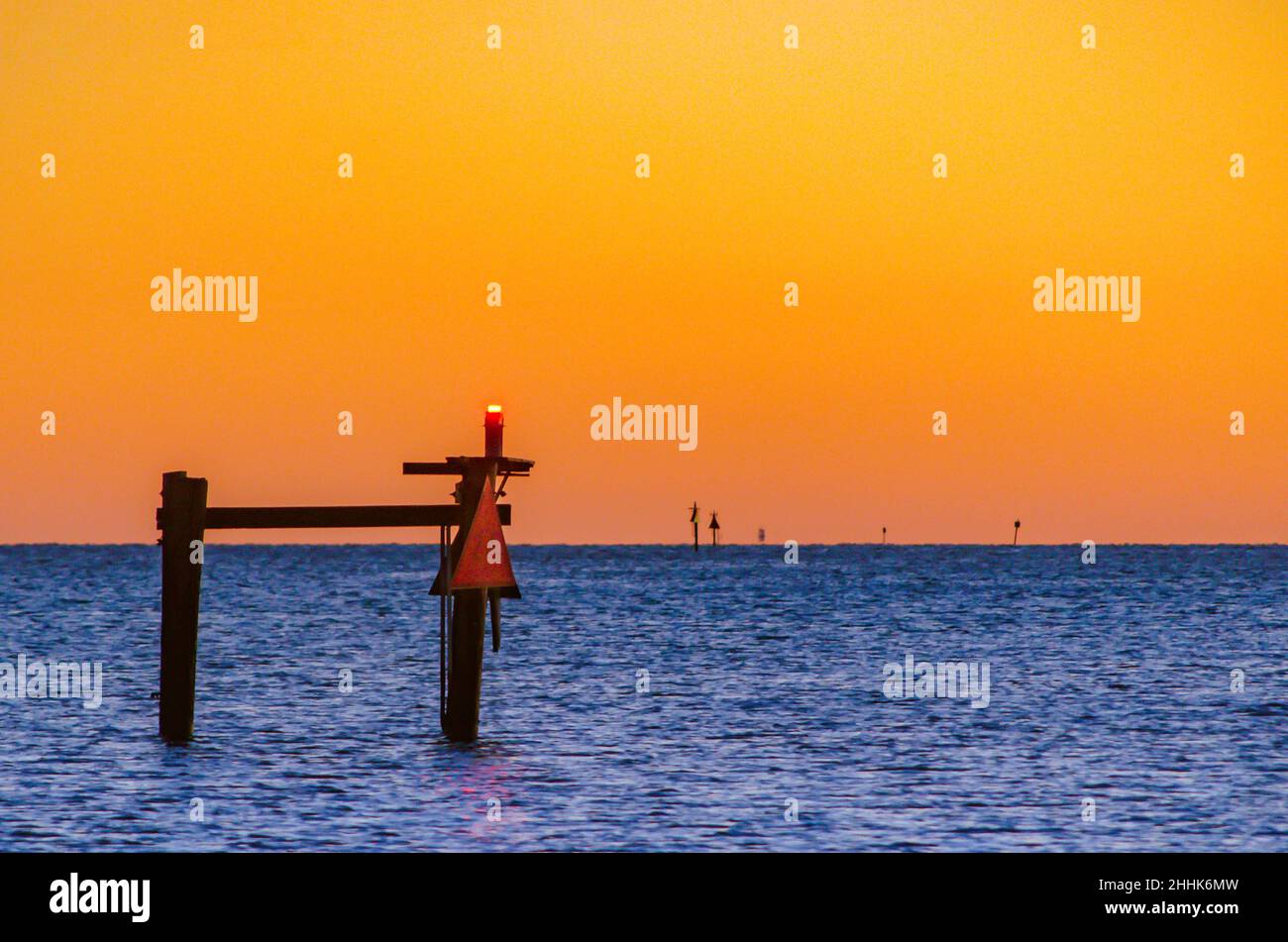 Am 4. Januar 2016, in Bayou La Batre, Alabama, wird in der Dämmerung ein Tagesfeuer angezündet, als die Sonne über dem Wasser untergeht. Stockfoto