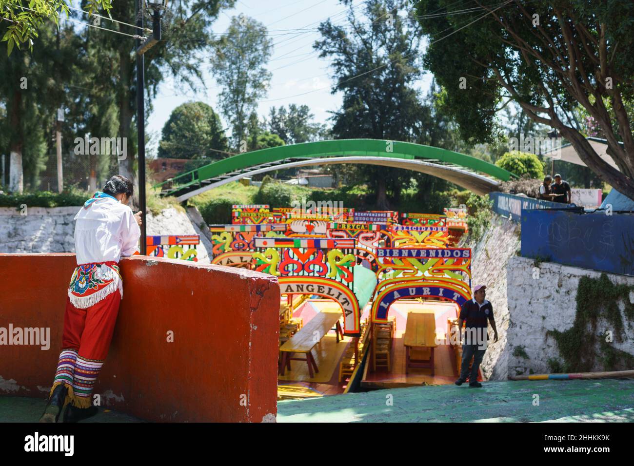 Einer der Totonac Voladores (Flyer) in Kostüm vor einer Vorstellung macht ein Handy-Foto der Xochimilco Touristenboote. Stockfoto