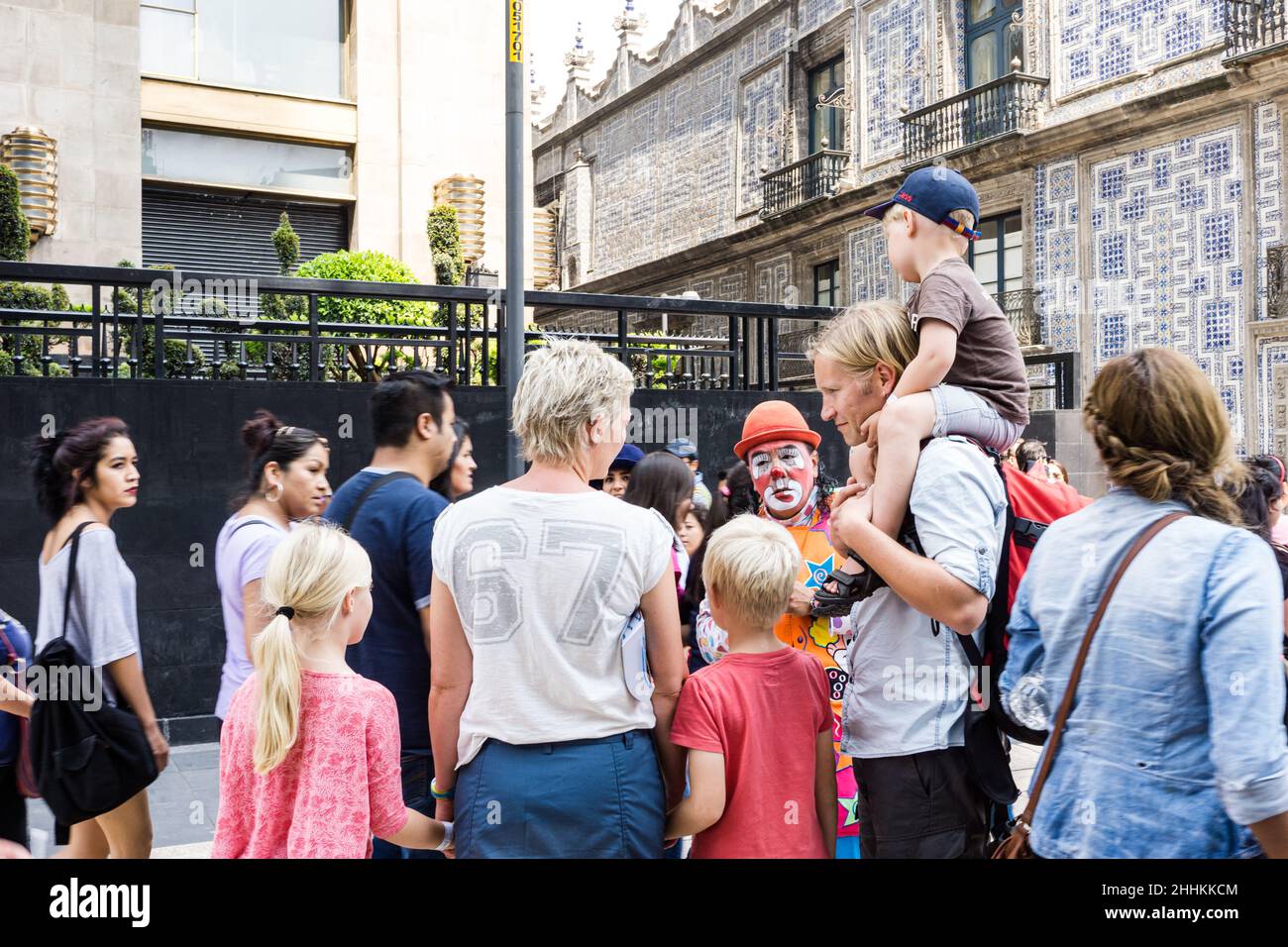 Eine blonde ausländische Touristenfamilie beobachtet einen mexikanischen Clown, der in der Nähe des Palastes der Schönen Künste auftrat Stockfoto