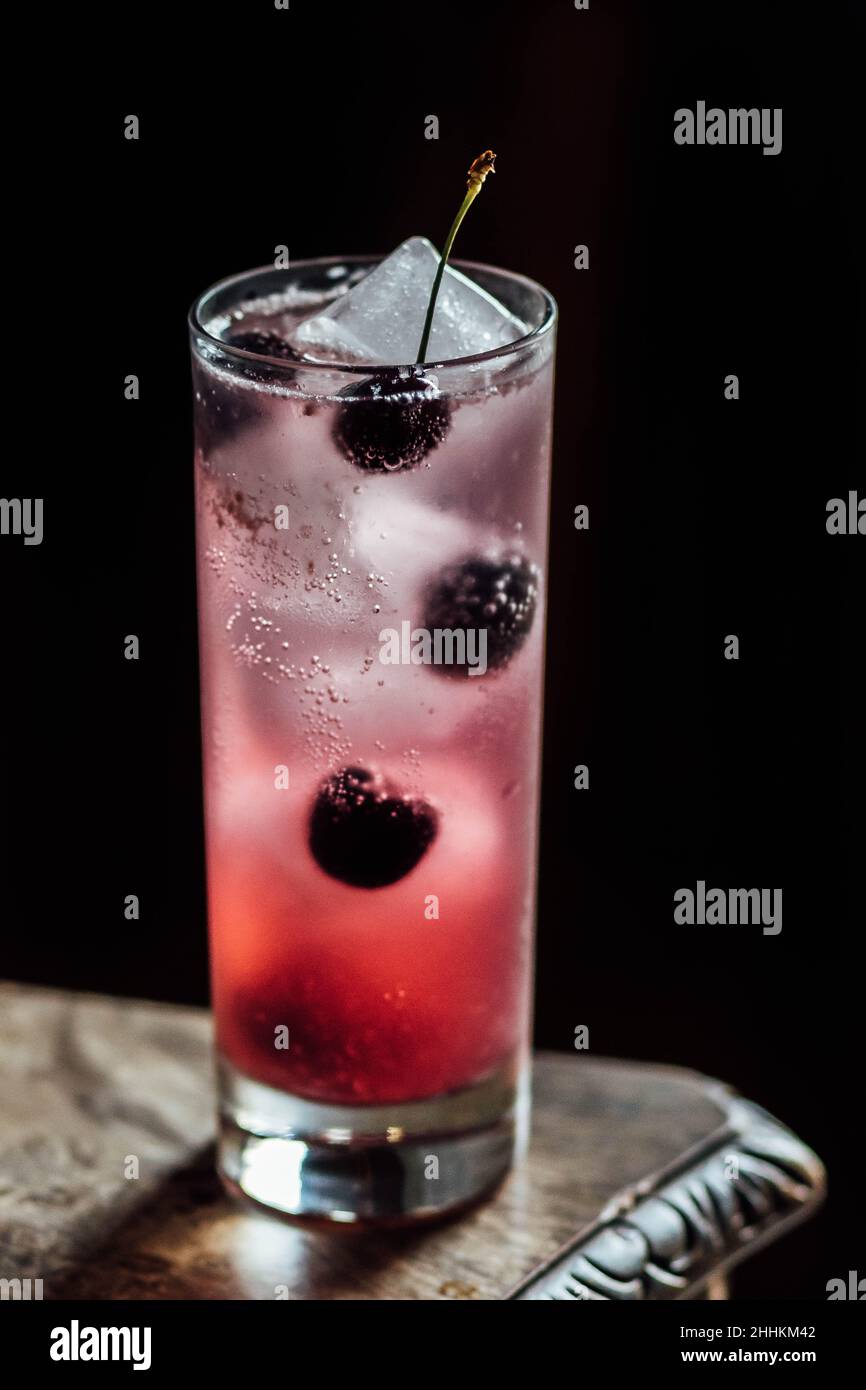 Schwarzer Kirschsoda-Cocktail mit Eis in hohem Glas Stockfoto