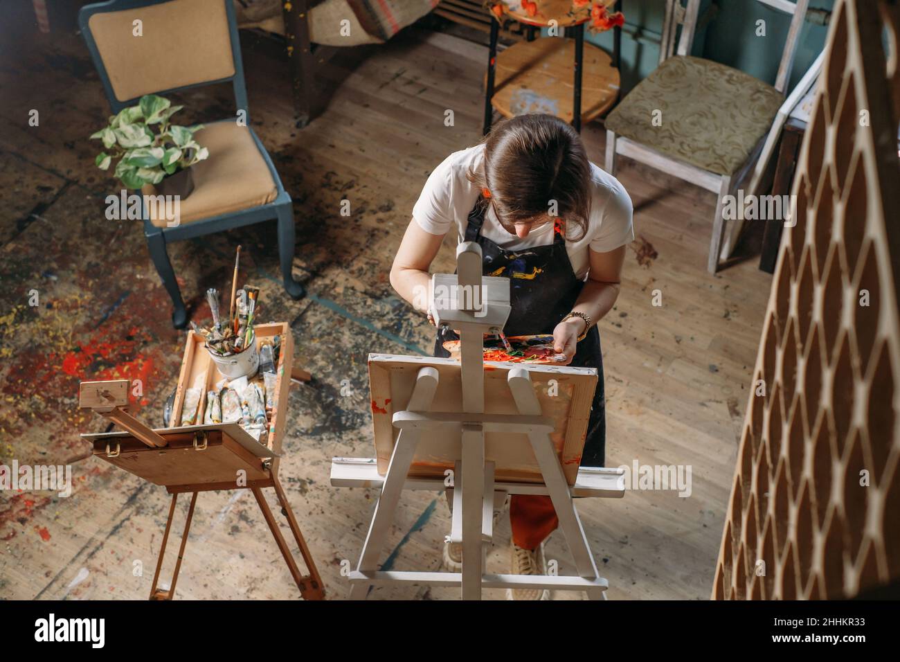 Maler, der in einem echten Atelier mit Ölfarben und Pinsel arbeitet, schafft Leinwand, moderne Kunst. Junger Mann mit Palette Nahaufnahme Stockfoto