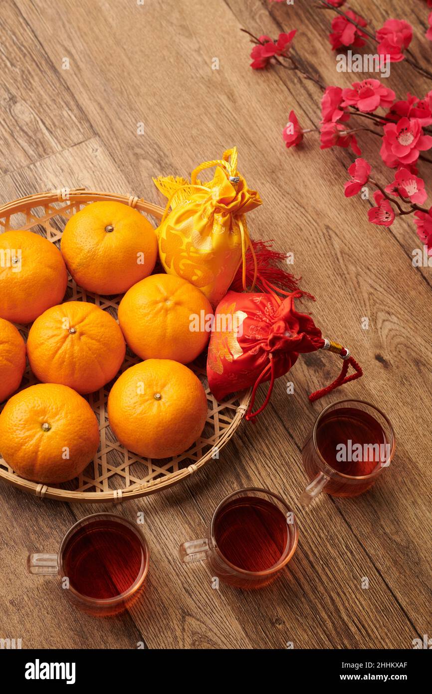 Frische Mandarinen, Tassen Tee und kleine Geschenktüten mit Glückstickereien Stockfoto