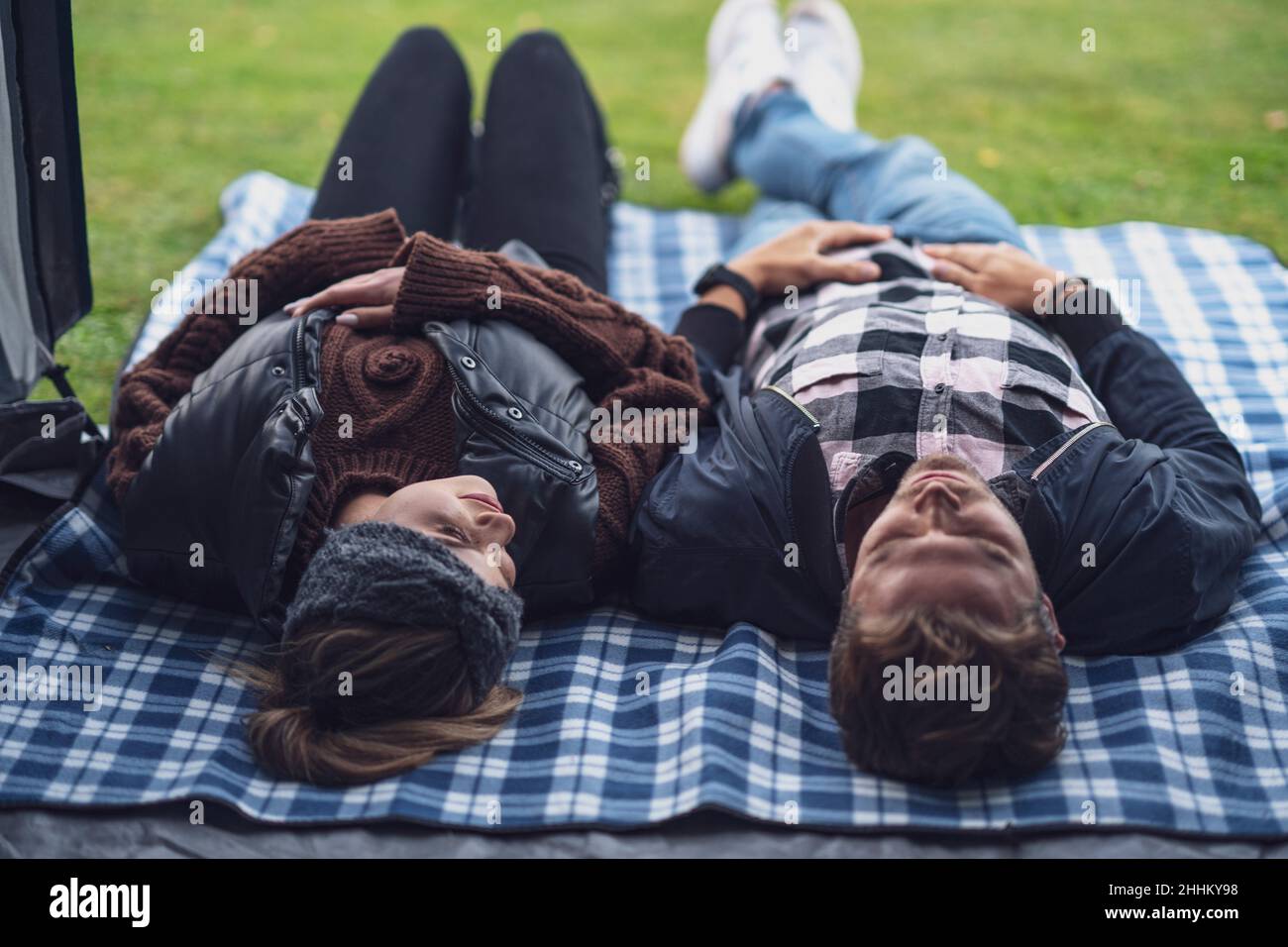 Junges nettes Paar, das Spaß auf dem Camping hat, im Zelt liegend Stockfoto