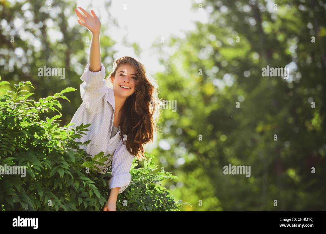 Freundliche Frau sagen Hallo Grüße auf Natur Hintergrund im Sommer oder Frühling Park. Stockfoto