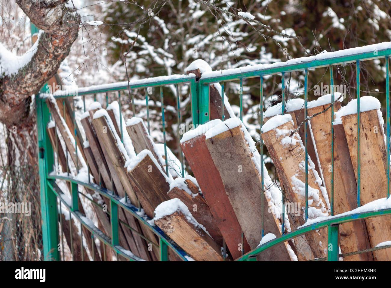 Stapel von alten rustikalen Brettern lehnte gegen den Zaun, Winterszene Stockfoto