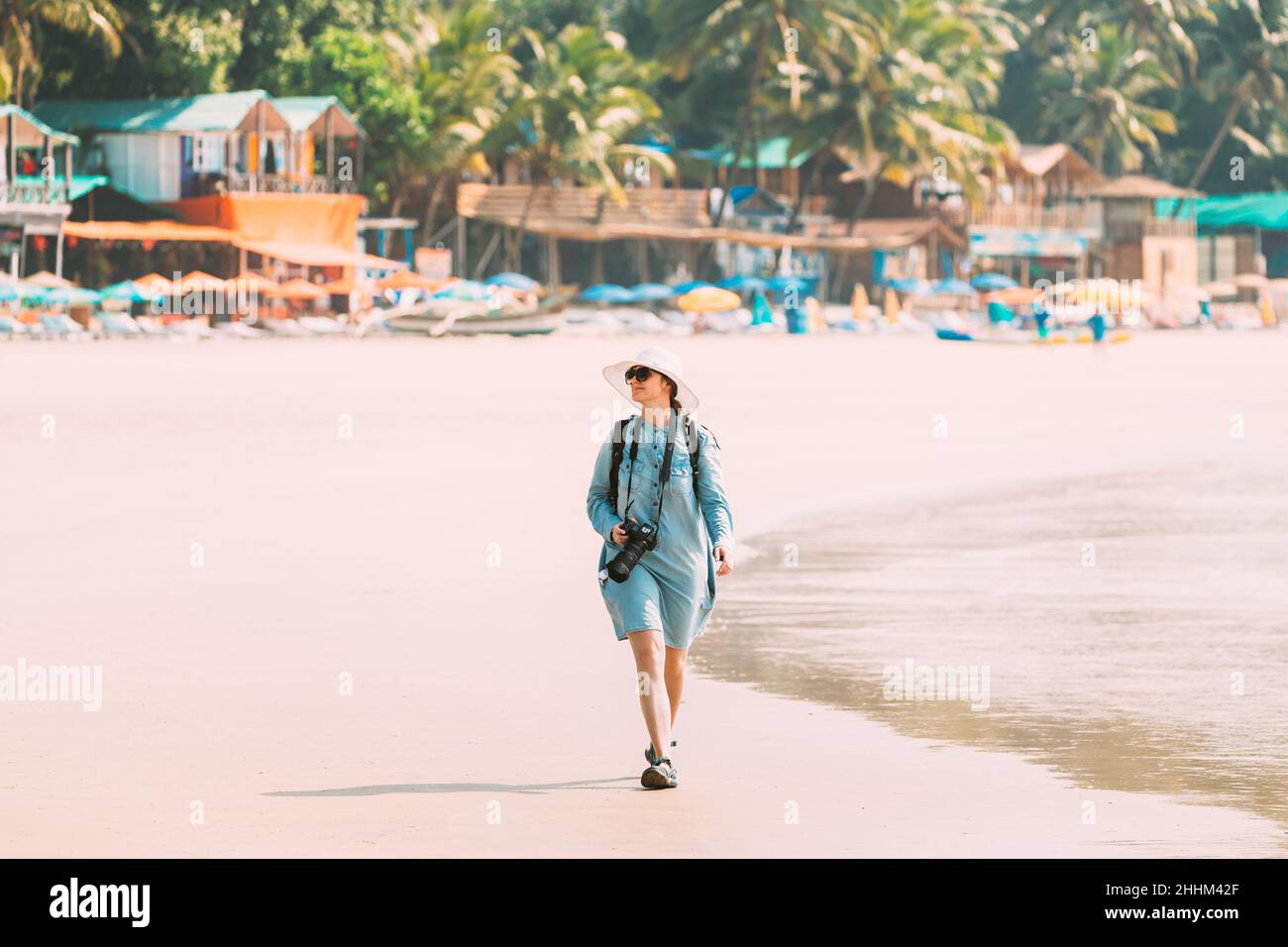 Canacona, Goa, Indien. Junge Kaukasische Frau Mit Kamera, Die Am Palolem Beach Entlang Der Küste Im Sommer An Sonnigen Tagen Spazierengeht Stockfoto