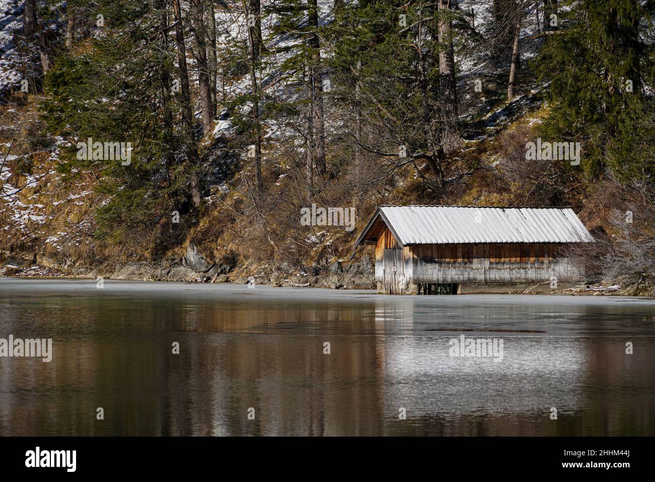 Ein kleines Strandhaus in der Winterlandschaft am Ufer des teilweise eisbedeckten Alpsees in Schwangau, Bayern. Stockfoto