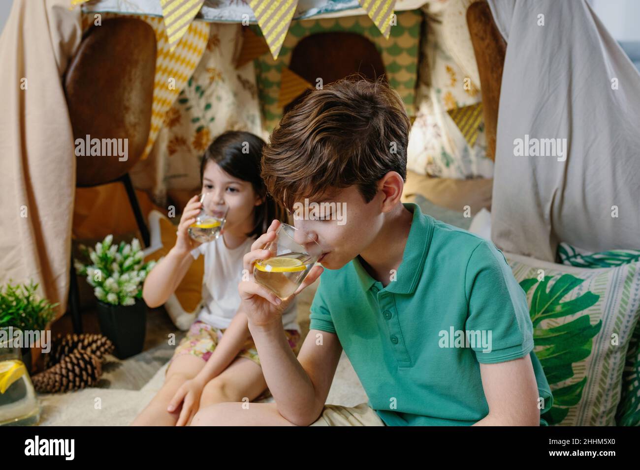 Junge trinkt hausgemachte Limonade mit seiner Schwester Stockfoto