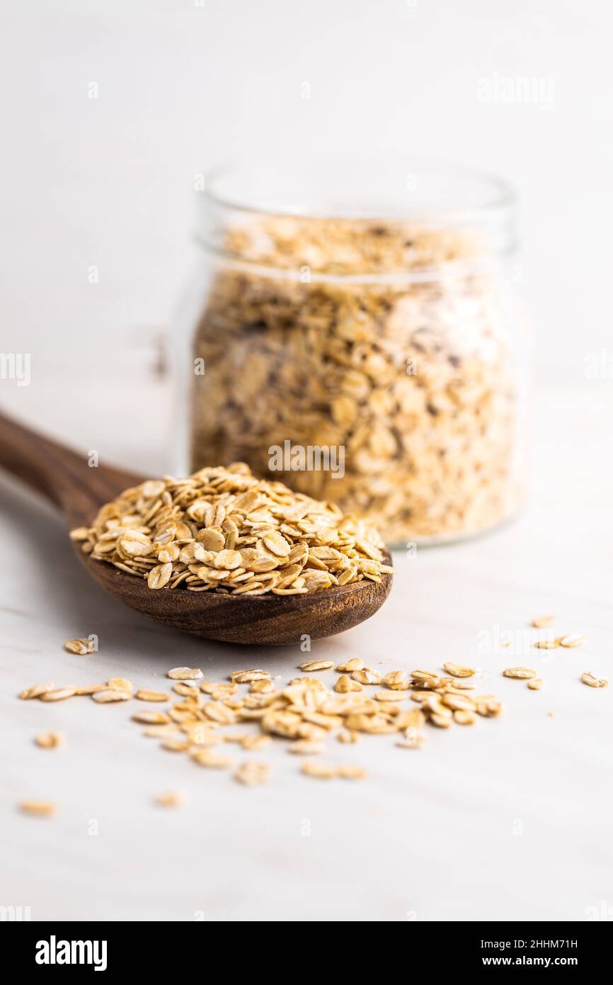 Frühstückscerealien. Ungekochte Haferflocken. Rohe Haferflocken in Holzlöffel. Stockfoto