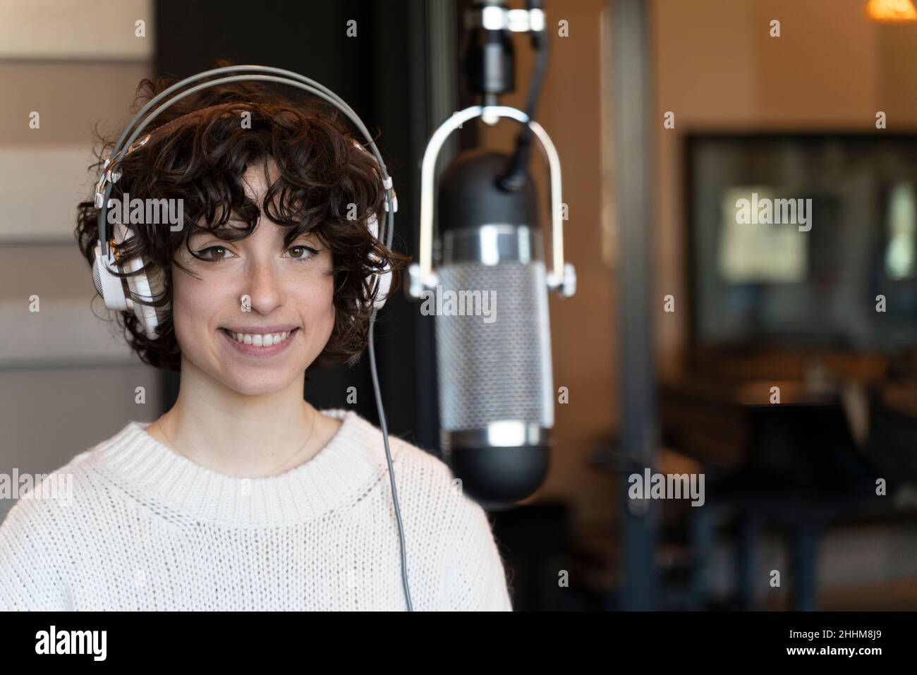 Eine junge Sängerin mit lockigen Haaren, die in einem echten Studio einen Song aufzeichnete Stockfoto