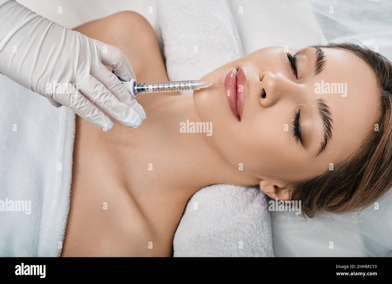 Frau während des Eingriffs Lippenvergrößerung in Kosmetologie Klinik mit Kosmetikerin. Filler Injektion für schöne weibliche Lippen Augmentation mit Hyaluron, Stockfoto