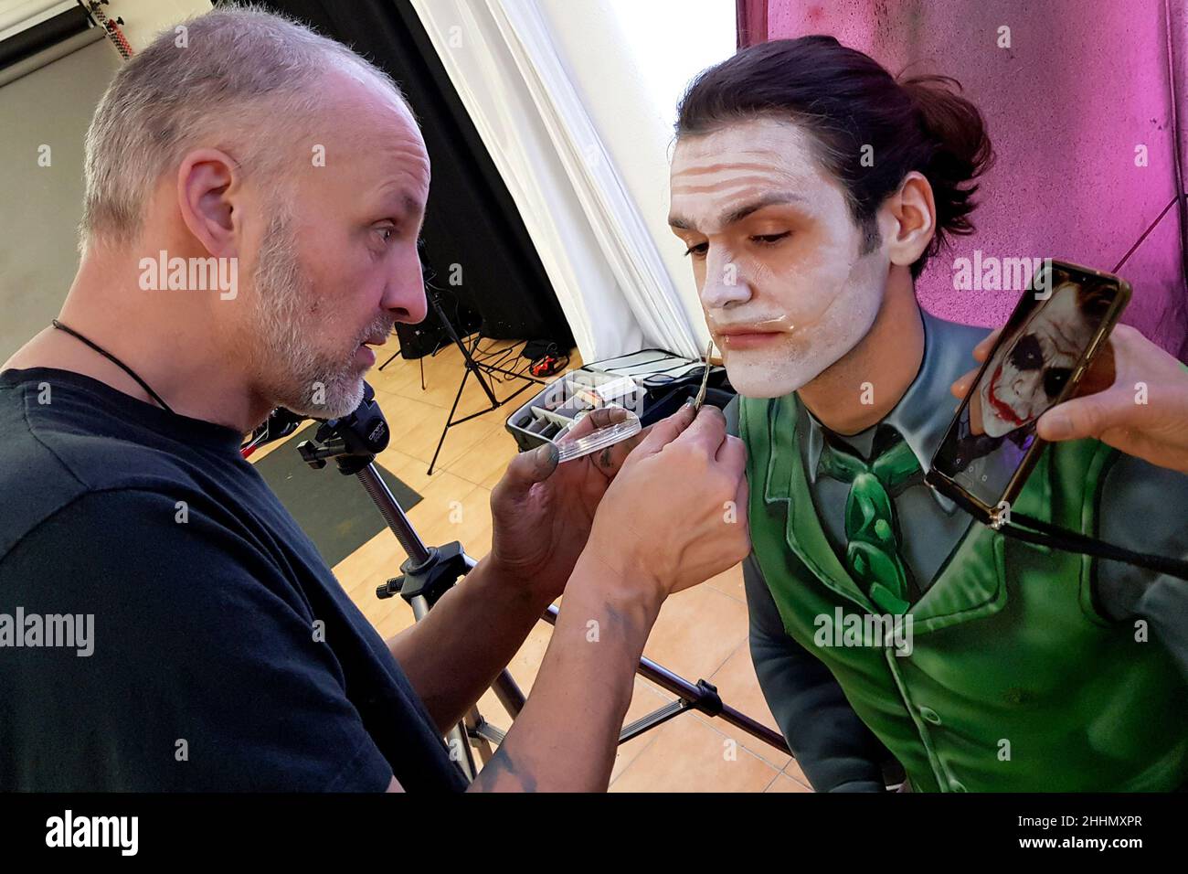 GEEK ART - Bodypainting und Transformaking: Enrico Lein bereitet den Joker vor trifft Riddler Fotoshooting mit Patrick Kiel als Joker im Duesterwald Studio am 23. Januar 2022 in Hamelin - Ein Projekt der Fotografin Tschiponnique Skupin und des Bodypainters Enrico Lein Stockfoto