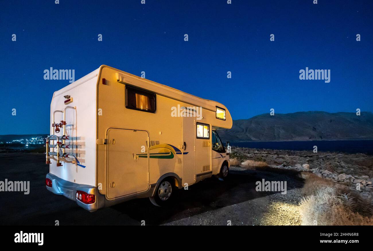 Wohnmobil RV geparkt unter Sternen auf einem Pier am Meer, Kreta, Griechenland. Reisende mit Wohnmobil ruhen sich auf einem aktiven Familienurlaub in K aus Stockfoto