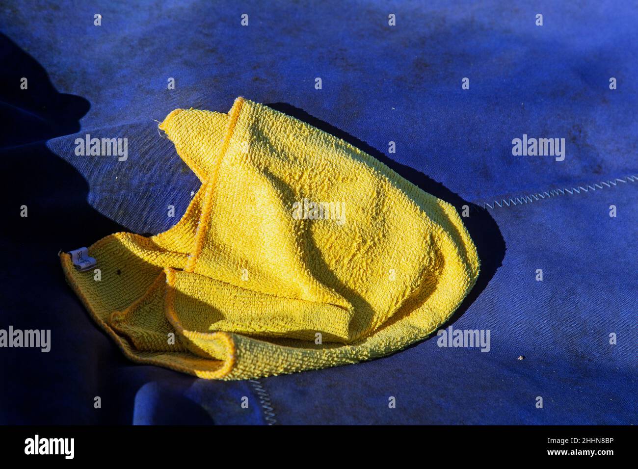 Rock, Cornwall, England, Januar 17th 2022, gelbes Staubtuch auf blauem Segeltuch. Stockfoto