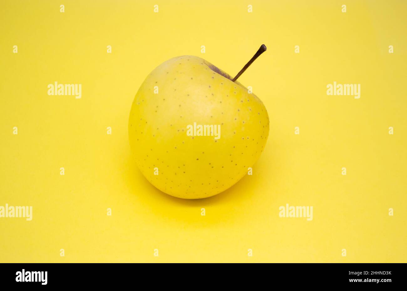 Gelber großer goldener Apfel auf gelbem Hintergrund. Speicherplatz kopieren. Stockfoto