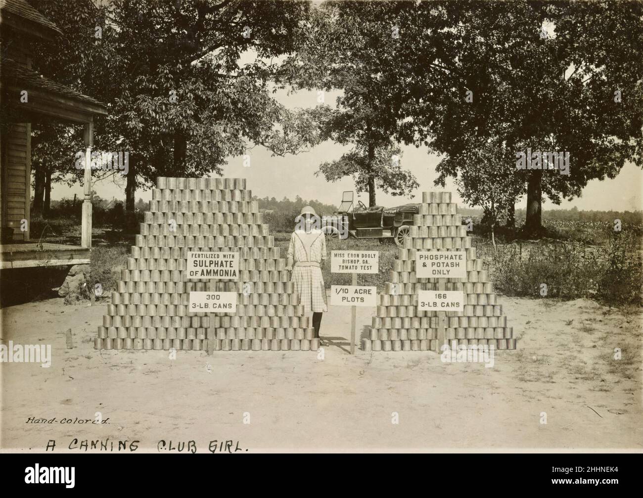 Frau Eron Dooley von Bishop, nahe Athen, Georgia, USA, steht zwischen zwei Stapeln Tomatendosen - frühes Canning Club-Foto - Anfang des 20. Jahrhunderts Stockfoto