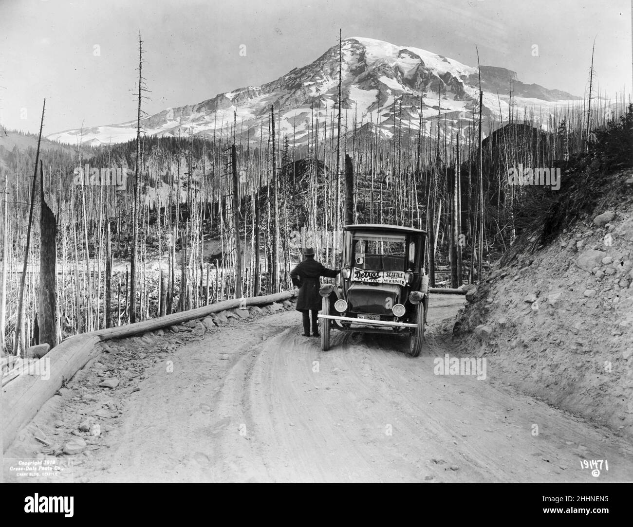 Ein Automobil von Detroit Electric hielt auf der Straße durch verbranntes Land, mit schneebedeckten Bergen im Hintergrund, Washington - um 1919 Stockfoto