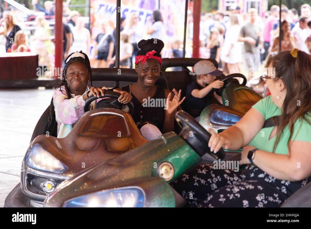 Multikulturelles Großbritannien, Menschen mit unterschiedlichem Hintergrund genießen die Stoßfänger Autos ( dodgem Autos), auf der Fun Fair, Hertfordshire, Großbritannien Stockfoto