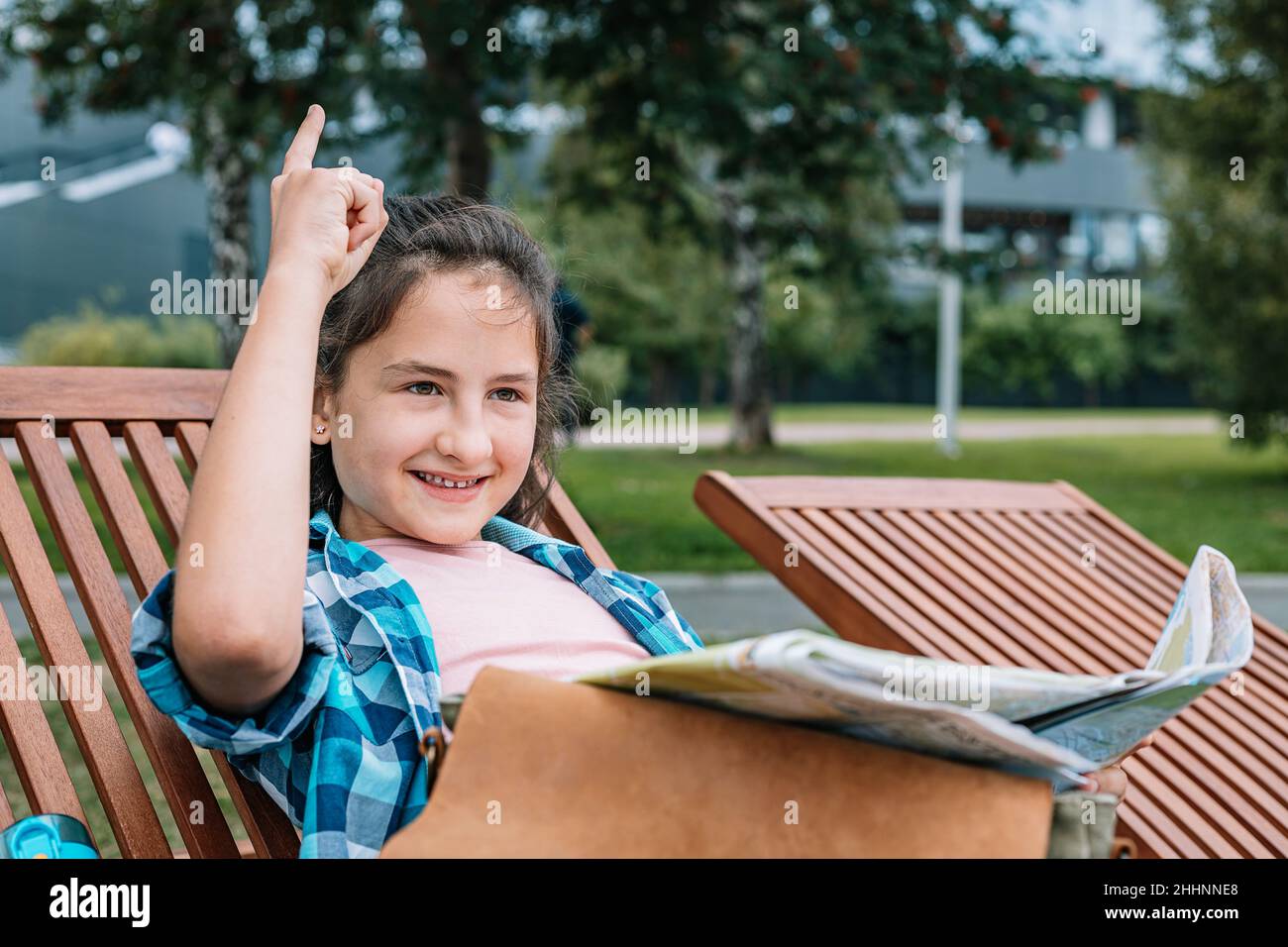 Positive junge Teenager-Mädchen mit einer Karte ruht auf einer Parkbank. Reisen im Sommerurlaub. Stockfoto
