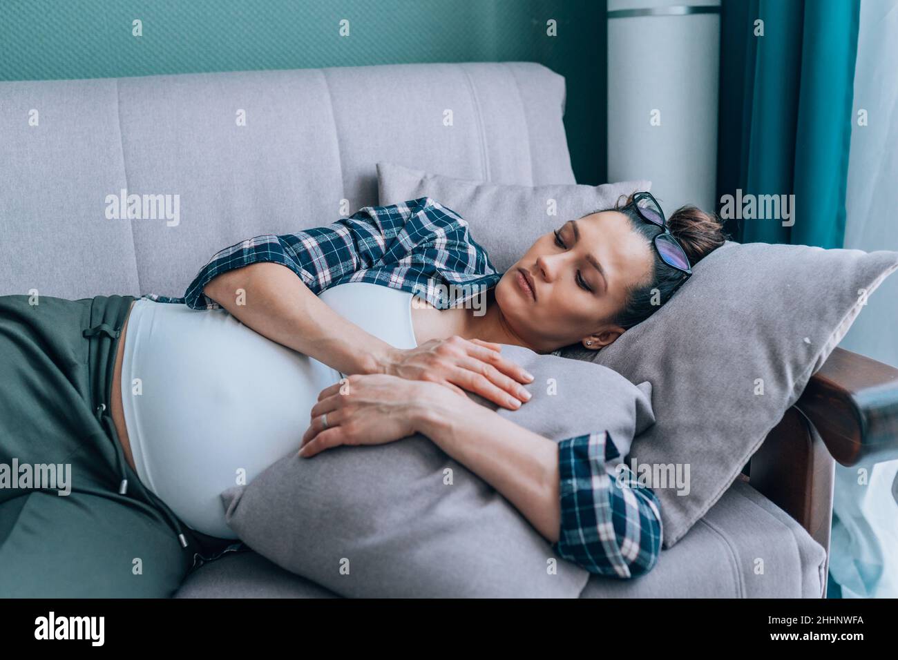 Junge traurige einsame Schwangerin, die zu Hause auf dem Sofa liegt und deprimierte Stimmung hat Stockfoto