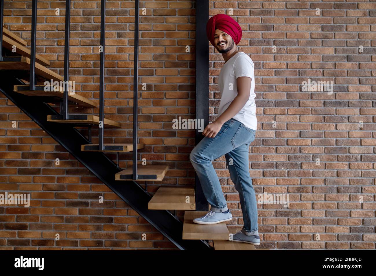 Junger inder im roten Turban, der auf Treppen steht Stockfoto