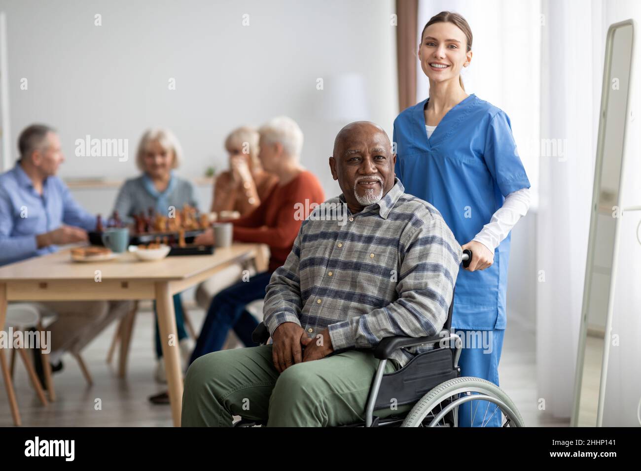 Glückliche ältere Patientin im Rollstuhl mit Krankenschwester Stockfoto