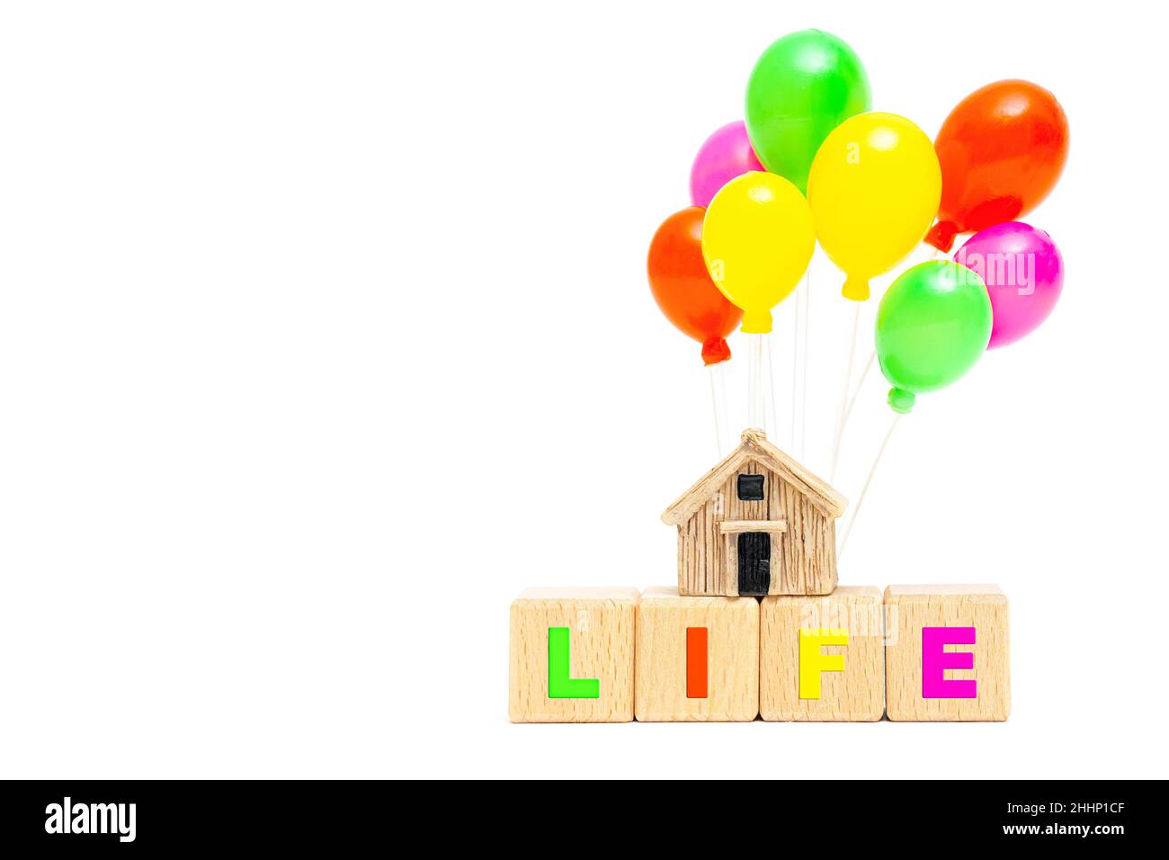 WORTLEBEN aus hölzernen Buchstabenblöcken und einem Miniatur-Hausmodell mit bunten Spielzeug-Ballons isoliert auf weißem Hintergrund. Häusliche Pflege hom Stockfoto