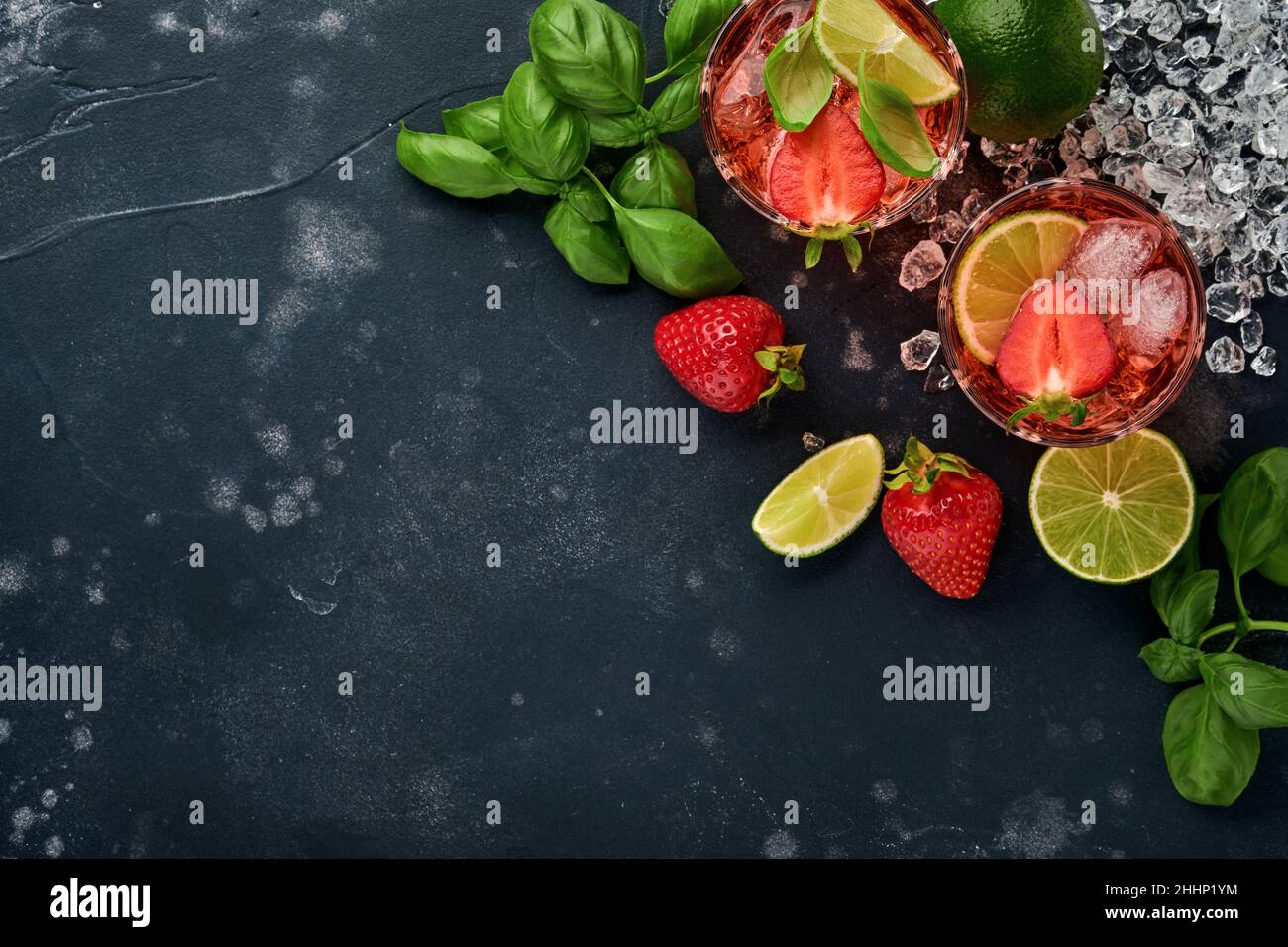 Punch-Cocktail. Zwei Gläser Punsch und frische Zutaten für die Herstellung von Limonade, infusem Detox-Wasser oder Cocktail. Erdbeeren, Limette, Minze, Basilikum, Eis Stockfoto