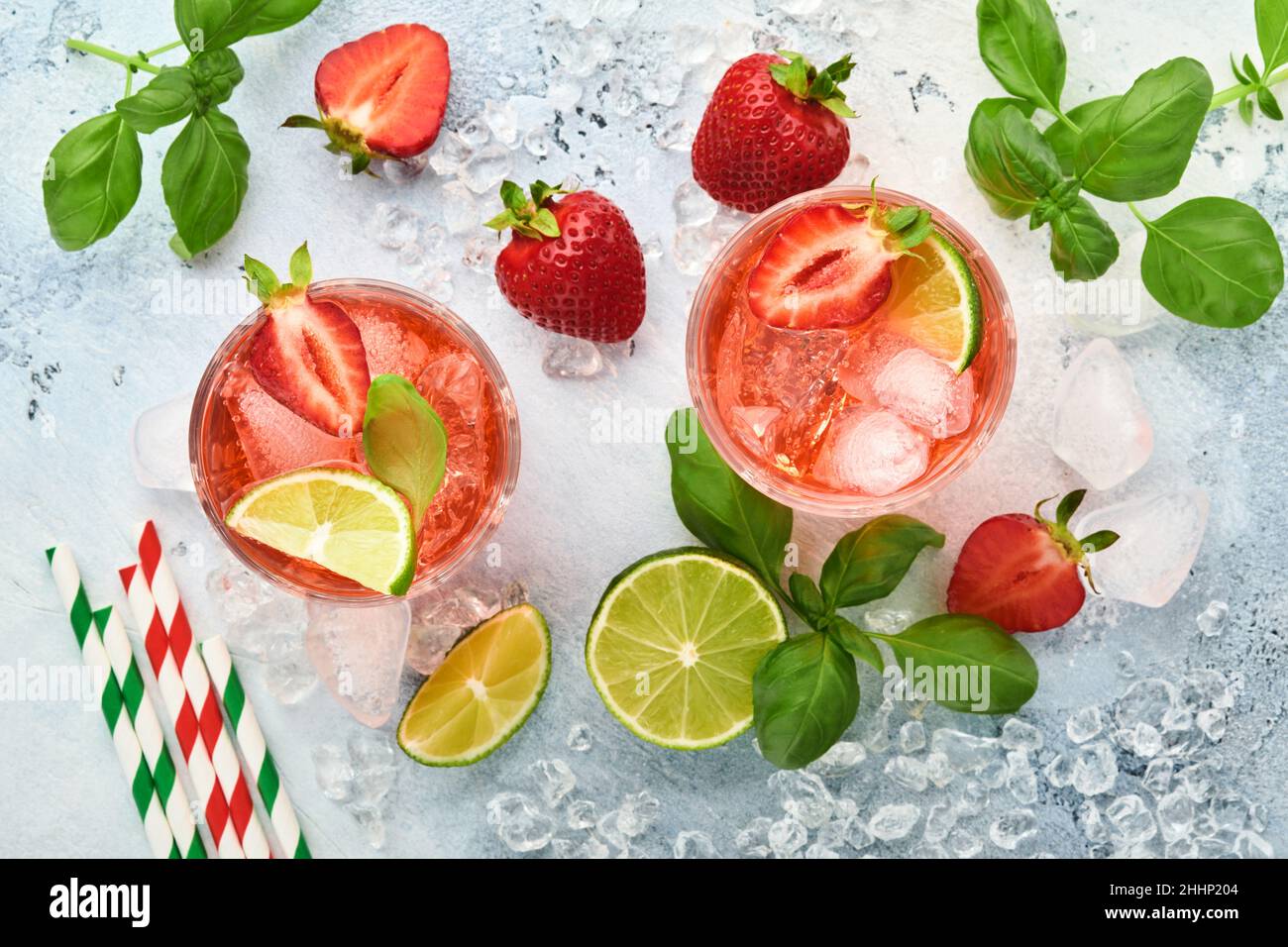 Punch-Cocktail. Zwei Gläser Punsch und frische Zutaten für die Herstellung von Limonade, infusem Detox-Wasser oder Cocktail. Erdbeeren, Limette, Minze, Basilikum, Eis Stockfoto