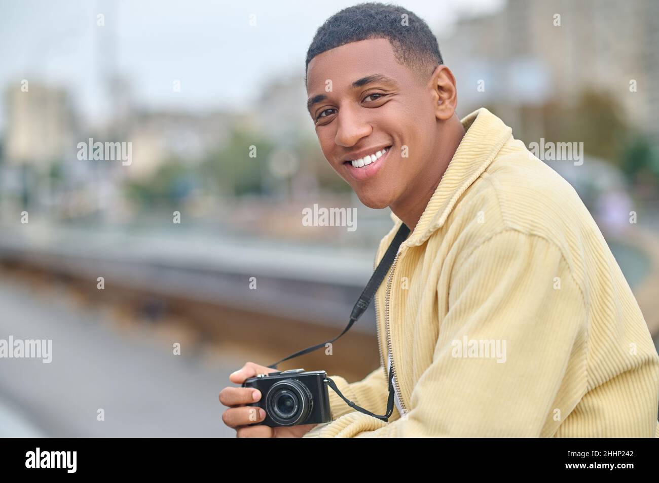 Mann, der die Fotokamera hält und die Kamera im Freien ansieht Stockfoto