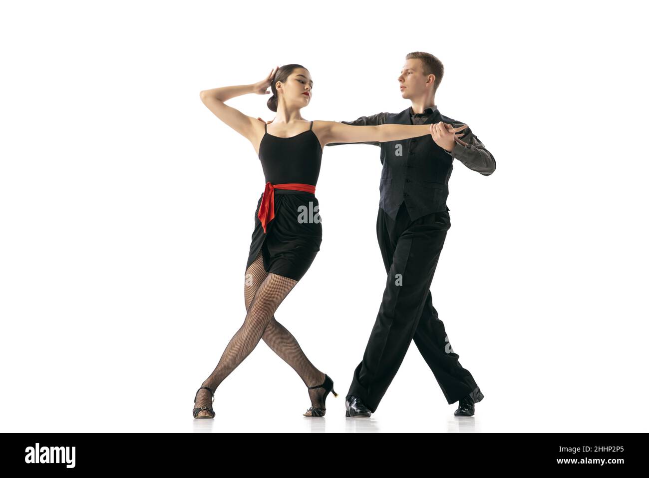 Anmut und schöne Tänzer, junges Paar, das argentinischen Tango tanzt, isoliert auf weißem Studiohintergrund. Künstler in schwarzen Bühnenkostümen Stockfoto