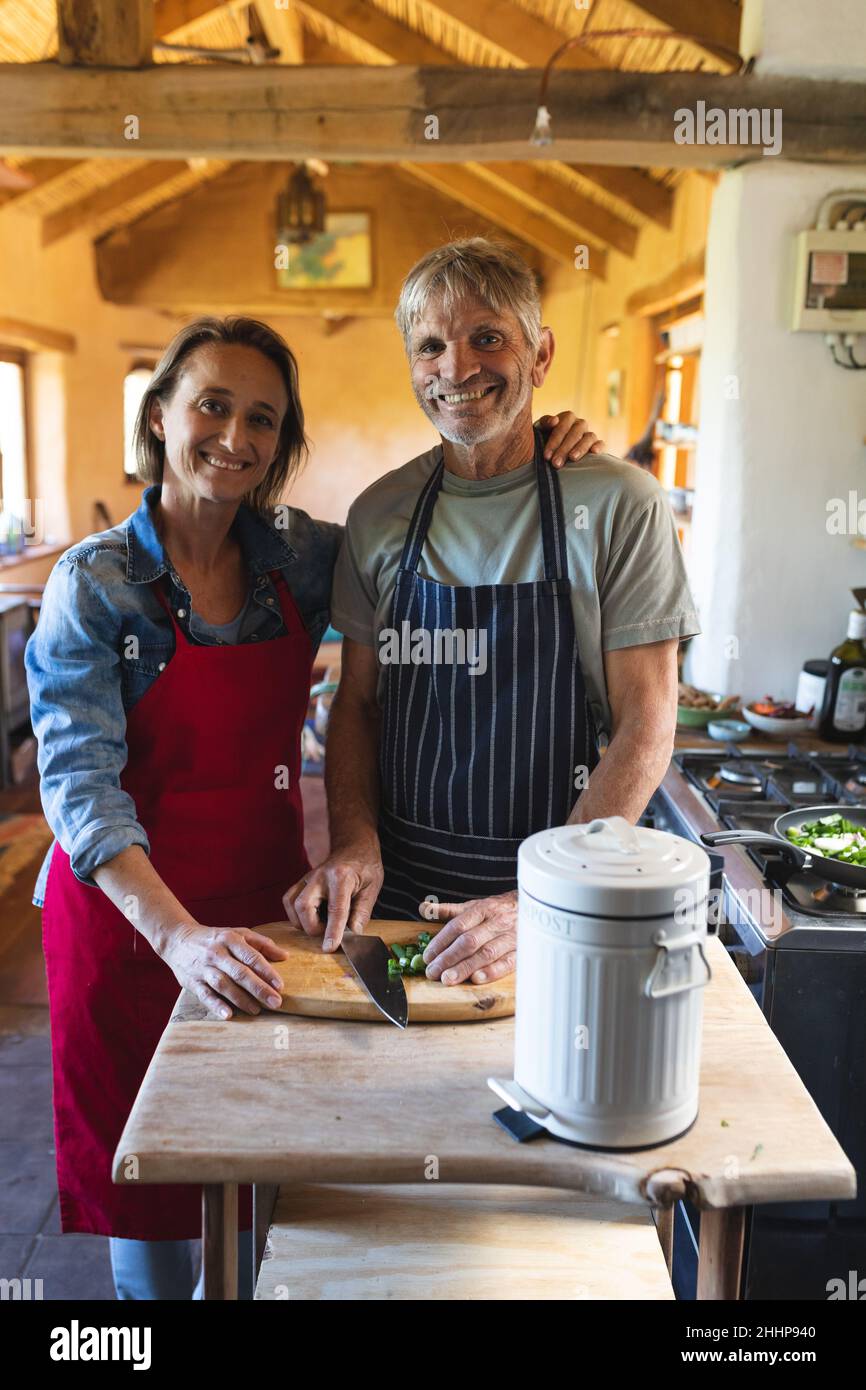 Portrait eines lächelnden kaukasischen reifen Paares, das in der Küche zu Hause zusammen kocht. Einfaches Leben, Zweisamkeit, Lifestyle und Kochen. Stockfoto