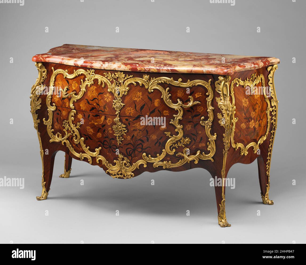 Kommode ca. 1760 Denis Genty Genty, der als Tischler und Möbelhändler tätig war, hat in seiner Intarsien-Dekoration die rollende Umrisse und Platzierung der Rokoko-Reittiere vorausgesagt. Die Halterungen schützten die Ecken, Füße und Schlüsselloch; gaben Zugang zu den Schubladen mittels Griffen; betonten die Serpentinform der Kommode; und fügten dem Stück ein skulpturales Element hinzu. Hier wurde die Hälfte der Reittiere entfernt, um ihre Bedeutung zu verdeutlichen. Die separate Eckhalterung zeigt von hinten, dass nur die Vorderseite vergoldet war. Die eingeschnittene Marke III entspricht der auf der st Stockfoto
