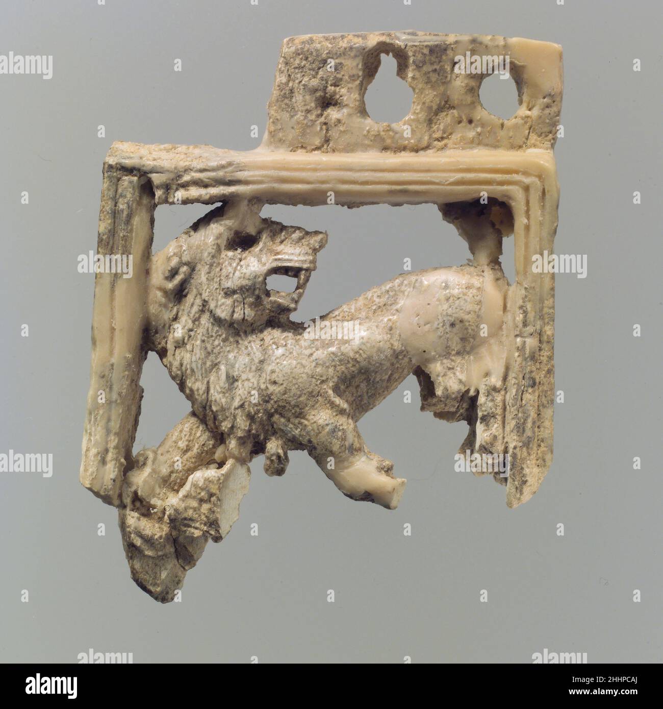 Durchbrochene Möbelplatte mit Löwe ca. 9th.–8th. Jahrhundert v. Chr. Assyrer Diese Elfenbeintafel wurde in einem Lagerraum in Fort Shalmaneser, einem königlichen Gebäude in Nimrud, gefunden, in dem Beute und Tribut aufbewahrt wurden, die von den Assyrern während des Militärfeldzuges gesammelt wurden. Es zeigt einen knarernden Löwen mit erhobener Hinterhand, umgedrehtem Kopf über seine Schulter, umrahmt von drei Seiten mit einem einfachen Rahmen, der von zwei parallelen vertikalen Linien verziert ist. Der Löwe ist in der durchbrochenen Technik geschnitzt, bei der der Hintergrund weggeschnitten und die restlichen Elemente in der Runde geschnitzt werden. Das Auge wurde für die Insertio gebohrt Stockfoto