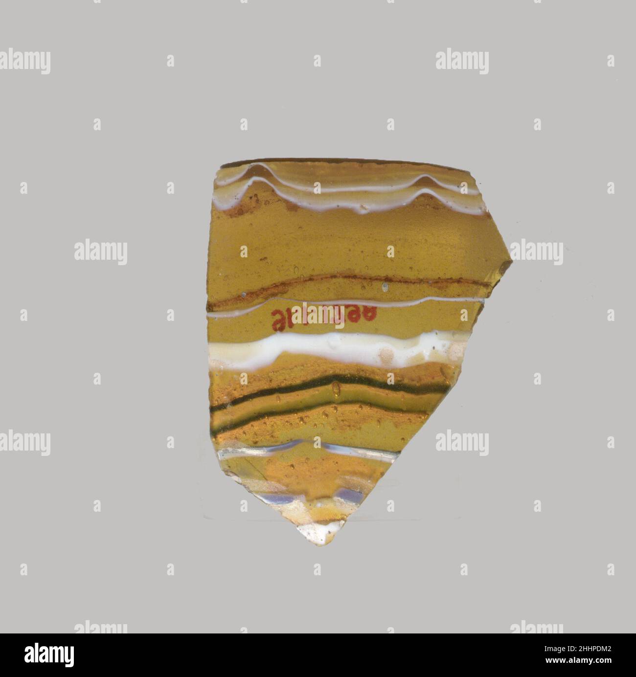 Glasmosaik-Schalenfragment Ende des 1st. Jahrhunderts v. Chr.–Anfang des 1st. Jahrhunderts n. Chr. Römisches dünnwandiges Körperfragment.Translucent honigbraun, blau und opakes Weiß.Convex geschwungene Seite.Mosaikmuster aus einer oder mehreren Stöcken in braunem Boden mit welligen weißen und blauen Fäden in parallelen Linien. Lochfraß von Oberflächenblasen auf der Außenseite; stumpfende und cremig schillernde Verwitterung auf der Innenseite und gezackte Kanten. Fragment der Glasmosaik-Schale. Römisch. Spätes 1st Jahrhundert B.C.–frühes 1st Jahrhundert A.D.. Glas; Guss. Frühkaiserlich. Glas Stockfoto