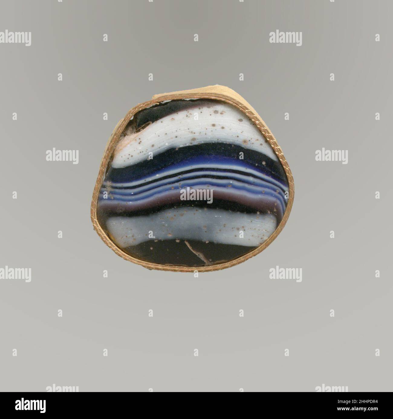 Glasmosaikfragment Ende des 1st. Jahrhunderts v. Chr.–Anfang des 1st. Jahrhunderts n. Chr. dickes römisches Basisfragment, wahrscheinlich aus einer tiefen, mit Füßen gerippten Schale.Durchscheinend tiefviolett, kobaltblau und opakes Weiß.zwei Schichten verschmolzen und bildeten eine konvexe Scheibe.Außenschicht: Bandmosaikmuster aus Abschnitten eines einzelnen Rohres in violettem Boden mit weißen und blauen Fäden in parallelen Linien gebildet; Innenschicht: Spiralförmigem Mosaikmuster aus Abschnitten eines einzelnen Rohres in blauem Boden mit weißen Fäden gebildet.Polierte konvexe Außenseite; Lochfraß von Oberflächenblasen und Verwitterung in Rissen; Dullend, cremig verwittern, a Stockfoto