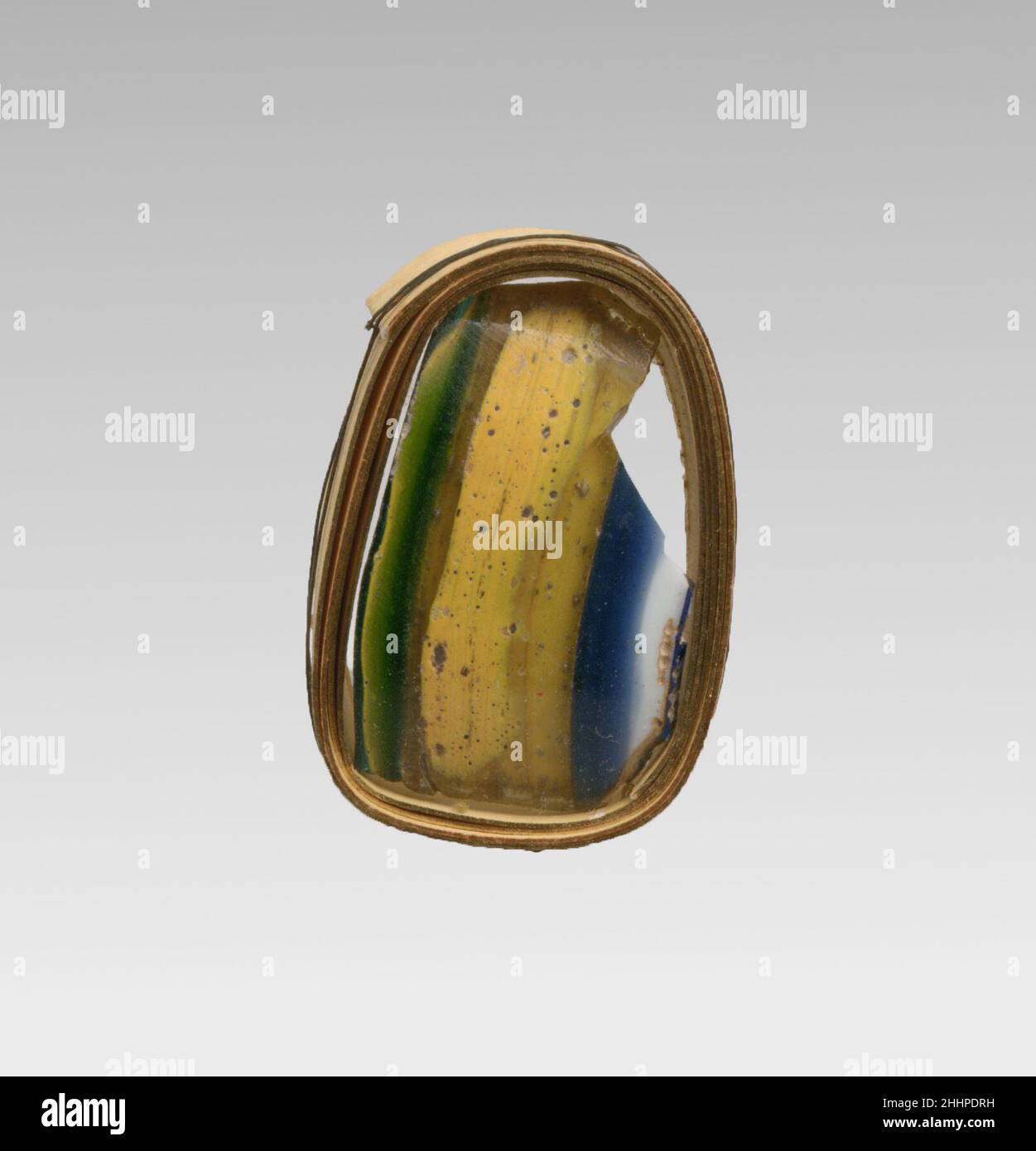 Glasmosaikfragment Ende des 1st. Jahrhunderts v. Chr.–Anfang des 1st. Jahrhunderts n. Chr. römisches Basisringfragment, wahrscheinlich aus einer tiefen, gerippten Schale. Lichtdurchlässiges Blau, Türkisblau mit opaken Gelbtönen und grünem, opaken Gelb und Weiß, Und farblos geradlinige, konische Seite mit abgerundetem unteren Rand.Ribbon Mosaik Muster aus Streifen in grün, gelb mit farblos, blau und weiß in parallelen Linien gebildet.Pinprick Blasen; polierte Außen-und Unterkante; Lochfraß von Oberflächenblasen auf der Außenseite; stumpfend und schwach cremig schillernden Verwitterung auf dem Inneren und gezackten Kanten.. Glasmosai Stockfoto