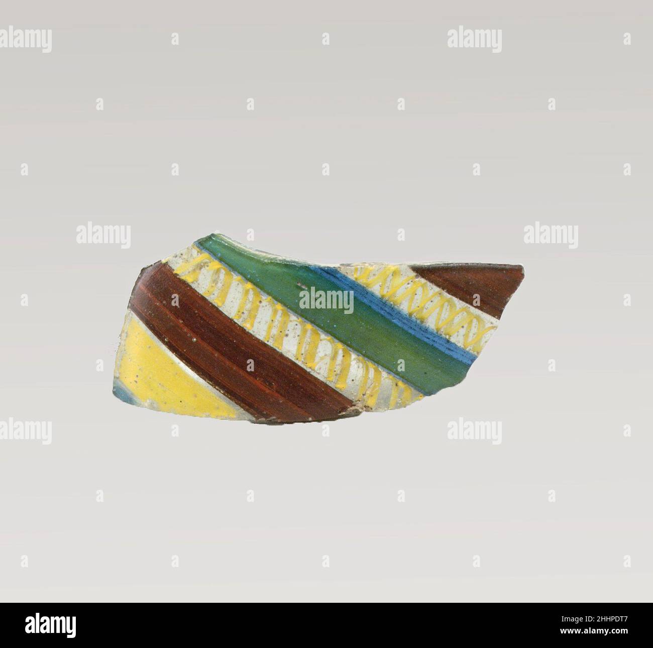 Glasstreifenmosaikfragment Ende des 1st. Jahrhunderts v. Chr.–Anfang des 1st. Jahrhunderts n. Chr. römisches Körperfragment.Durchscheinendes Blau, überwiegend blau mit Gelb, das matt grün erscheint, violett, undurchsichtig tiefes Ziegelrot und undurchsichtig gelb, mit farblosen Glas.Convex geschwungene Seite. Verziert mit breiten parallelen Bändern, die ein Muster bilden: Blau, gelb, rot, farblos mit doppelspiraligen gelben Fäden, grün, blau, farblos mit doppelspiraligen gelben Fäden und braun, mit dünnen Trennlinien aus farbloßem Glas.Pinprickblasen; außen poliert, mit Lochfraß von Oberflächenblasen; stumpfes und irisierendes Wea Stockfoto