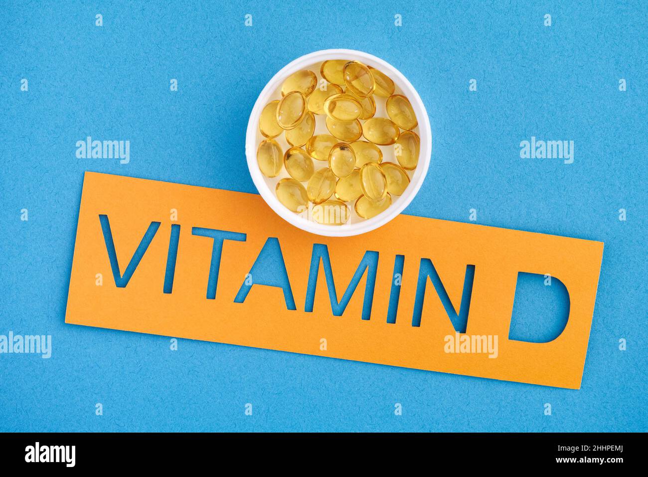 Das Wort Vitamin D mit einer kleinen Tasse Vitamin D3 Kapseln darauf. Nahaufnahme. Stockfoto