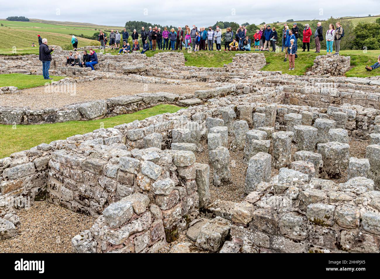 Eine Gruppe, die eine Führung durch die Ruinen der römischen Hilfsfestung Vindolanda in Chesterholm, Northumberland, Großbritannien, macht Stockfoto