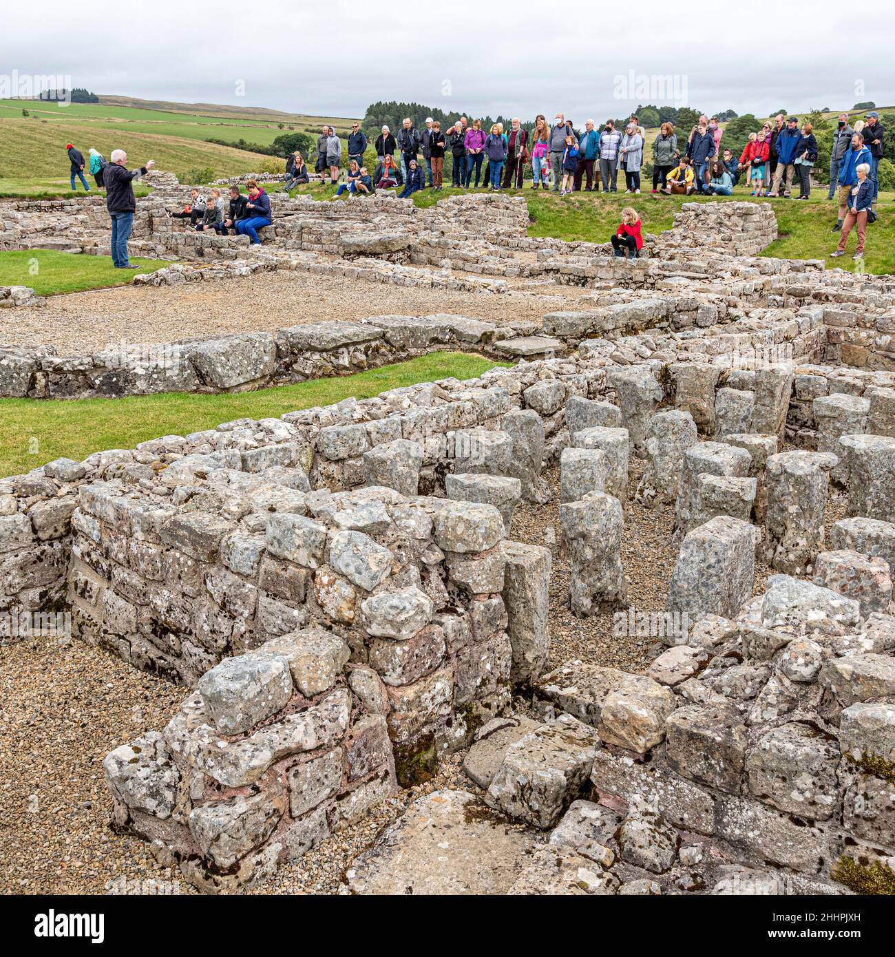 Eine Gruppe, die eine Führung durch die Ruinen der römischen Hilfsfestung Vindolanda in Chesterholm, Northumberland, Großbritannien, macht Stockfoto