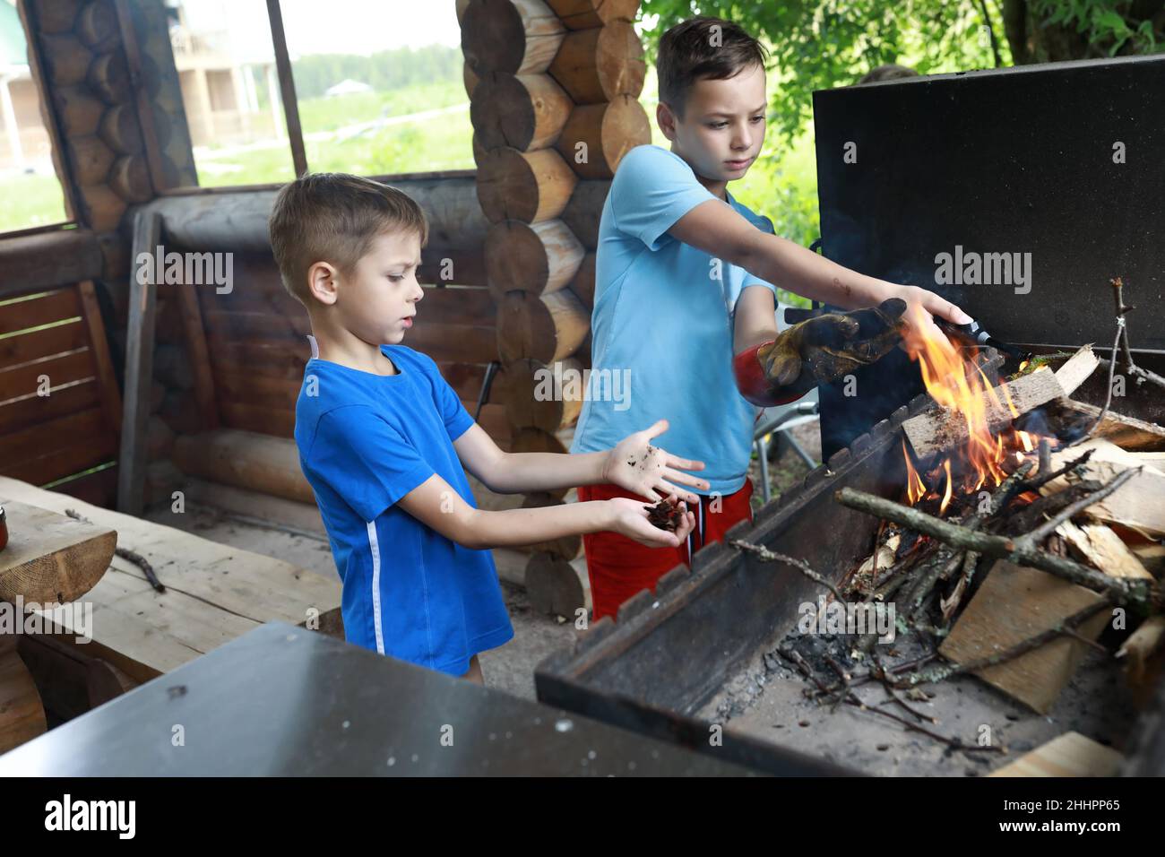 Zwei Kinder zünden Feuerholz im Grill an, Karelia Stockfoto