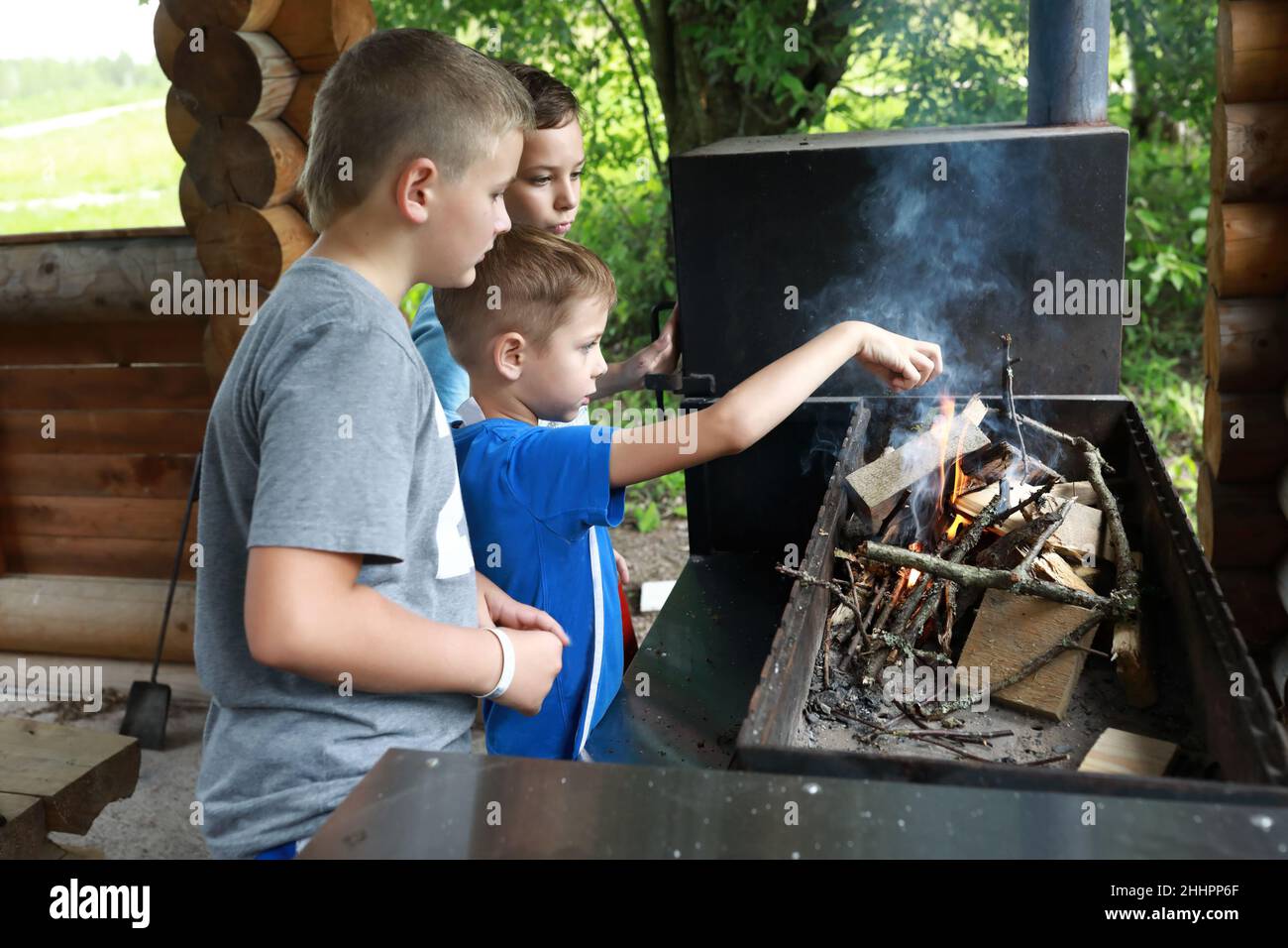 Drei Jungen zünden Feuerholz im Grill, Karelia Stockfoto