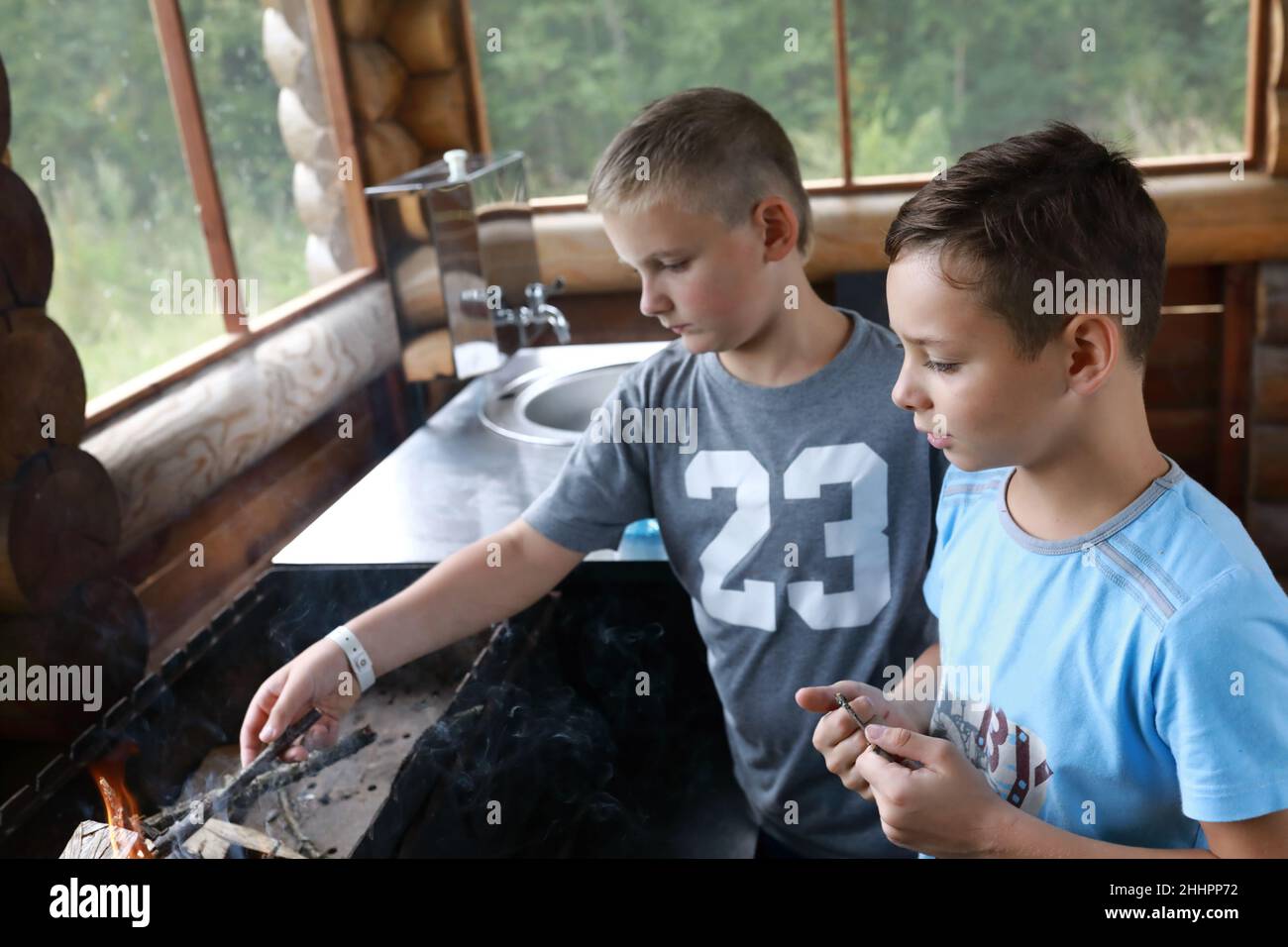 Zwei Kinder zünden Feuerholz im Grill, Karelia Stockfoto
